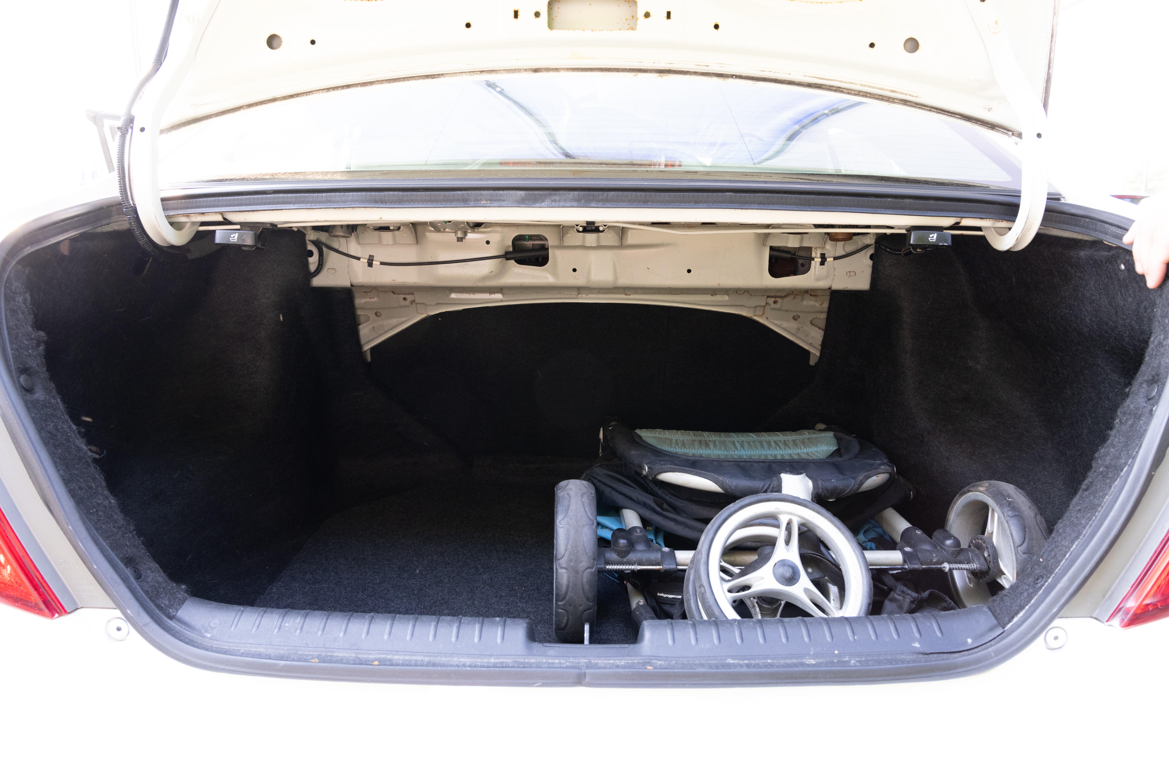 The trunk area is open giving a full view of the trunk area. A baby stroller, four grocery carriers, a yoga mat, and a set of golf clubs are placed inside.