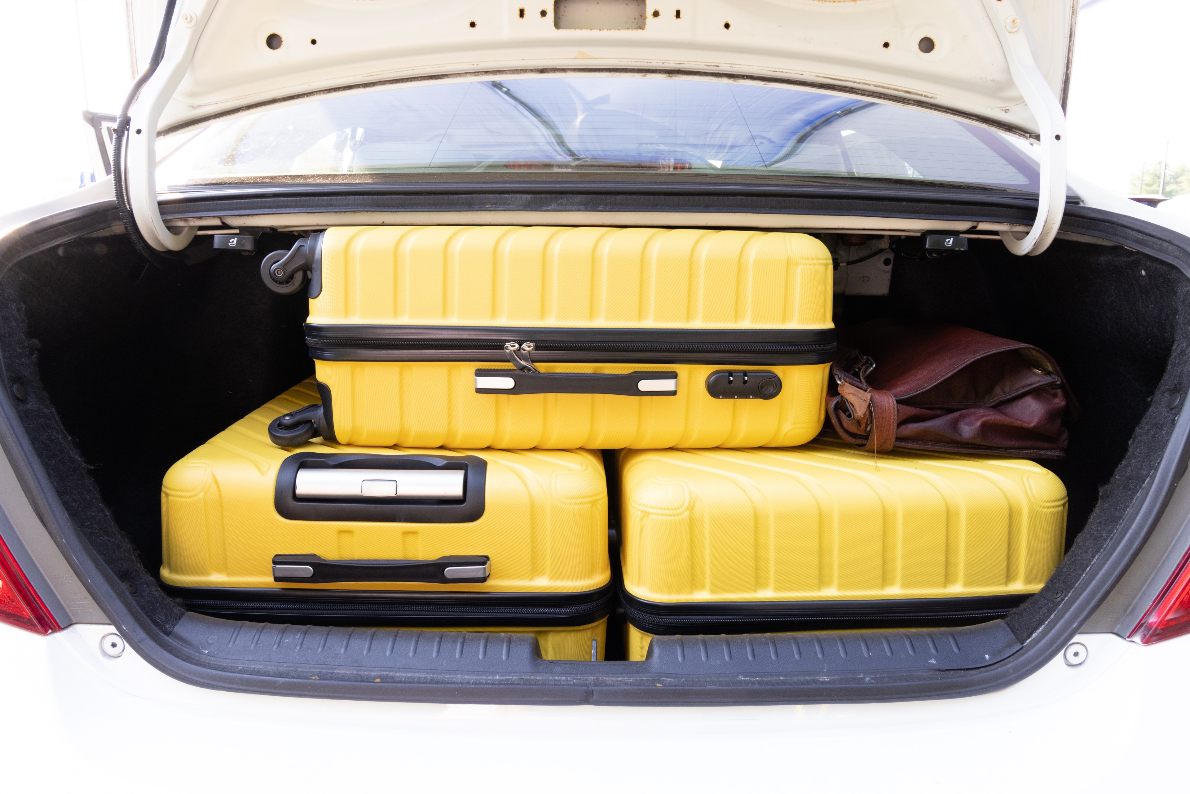 The trunk area is open giving a full view of the trunk area. Two large and two small suitcases are placed on their sides.