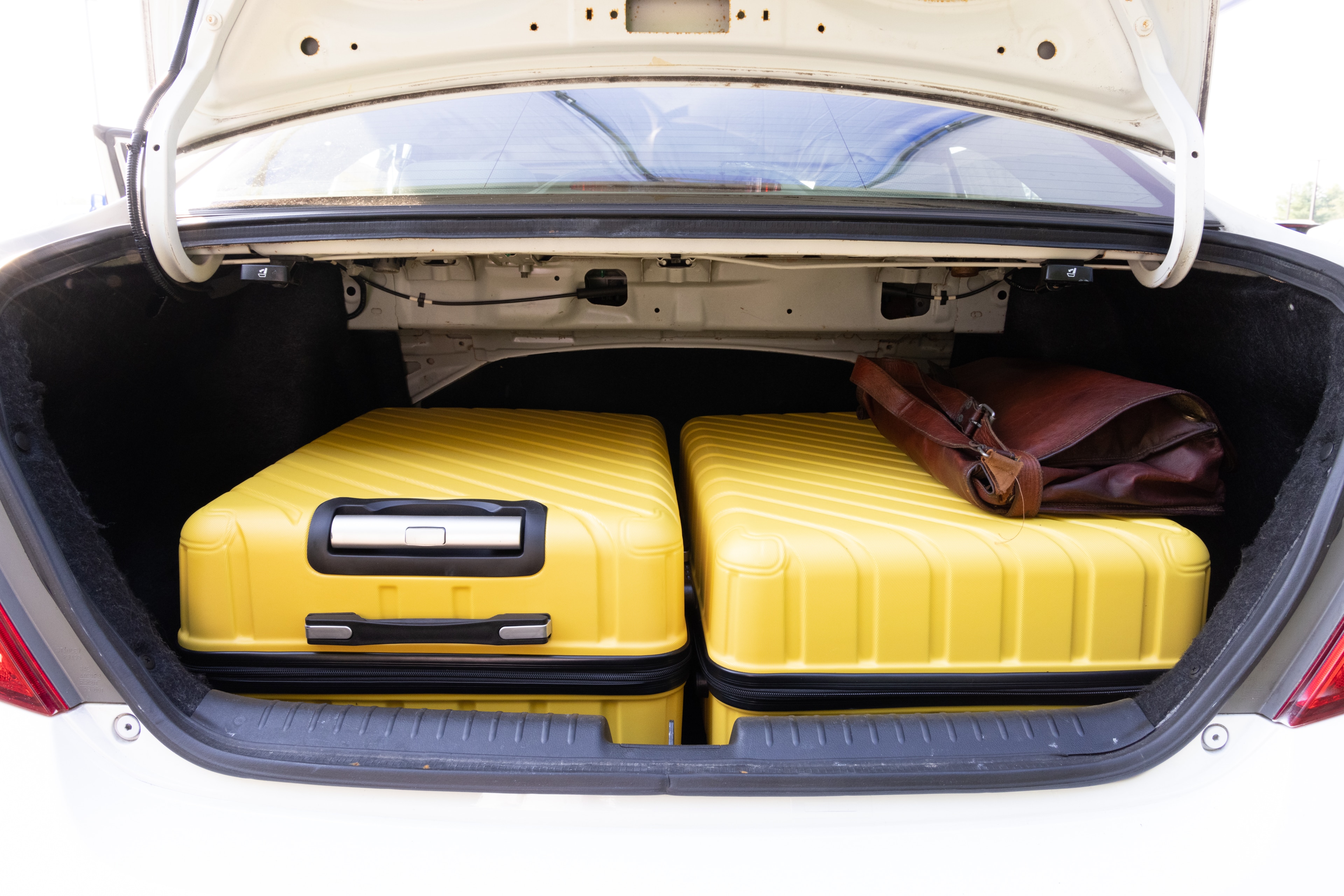 The trunk area is open giving a full view of the trunk area. Two large and two small suitcases are placed on their sides.