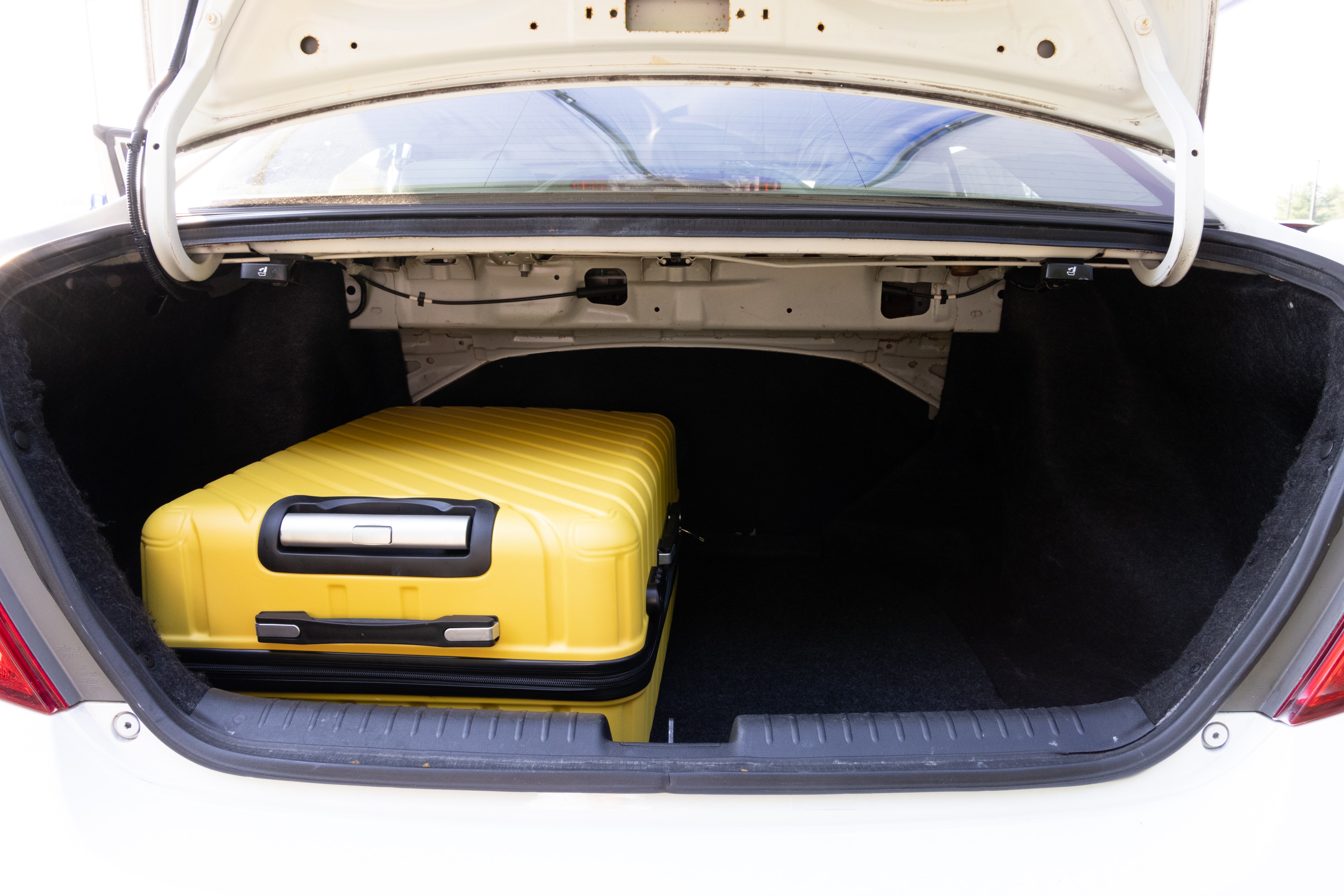 The trunk area is open giving a full view of the trunk area. Two large and two small suitcases are placed on their sides.