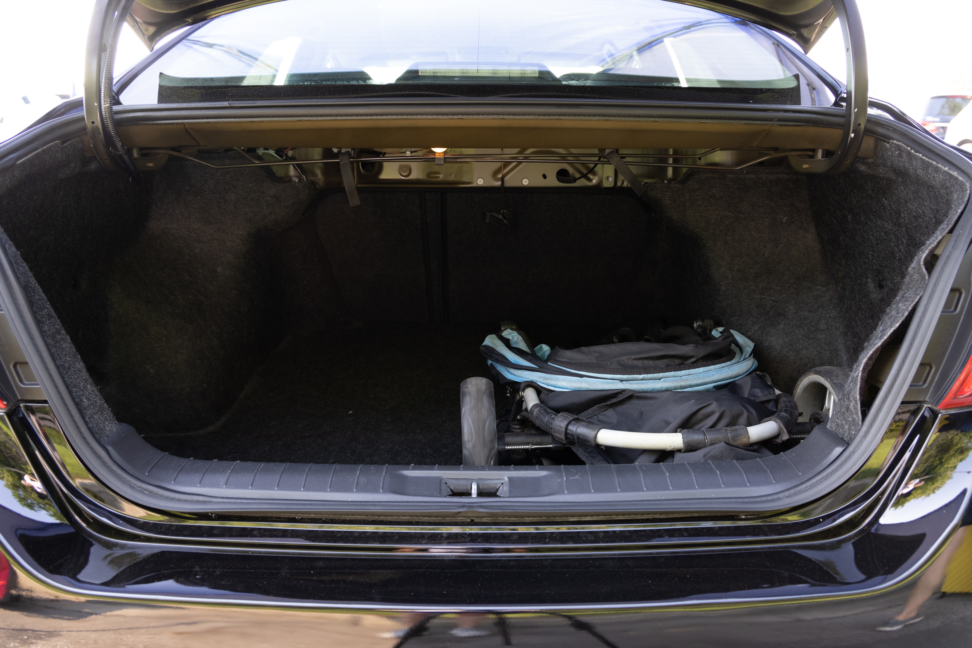 The trunk area is open giving a full view of the trunk area. A baby stroller, four grocery carriers, a yoga mat, and a set of golf clubs are placed inside.