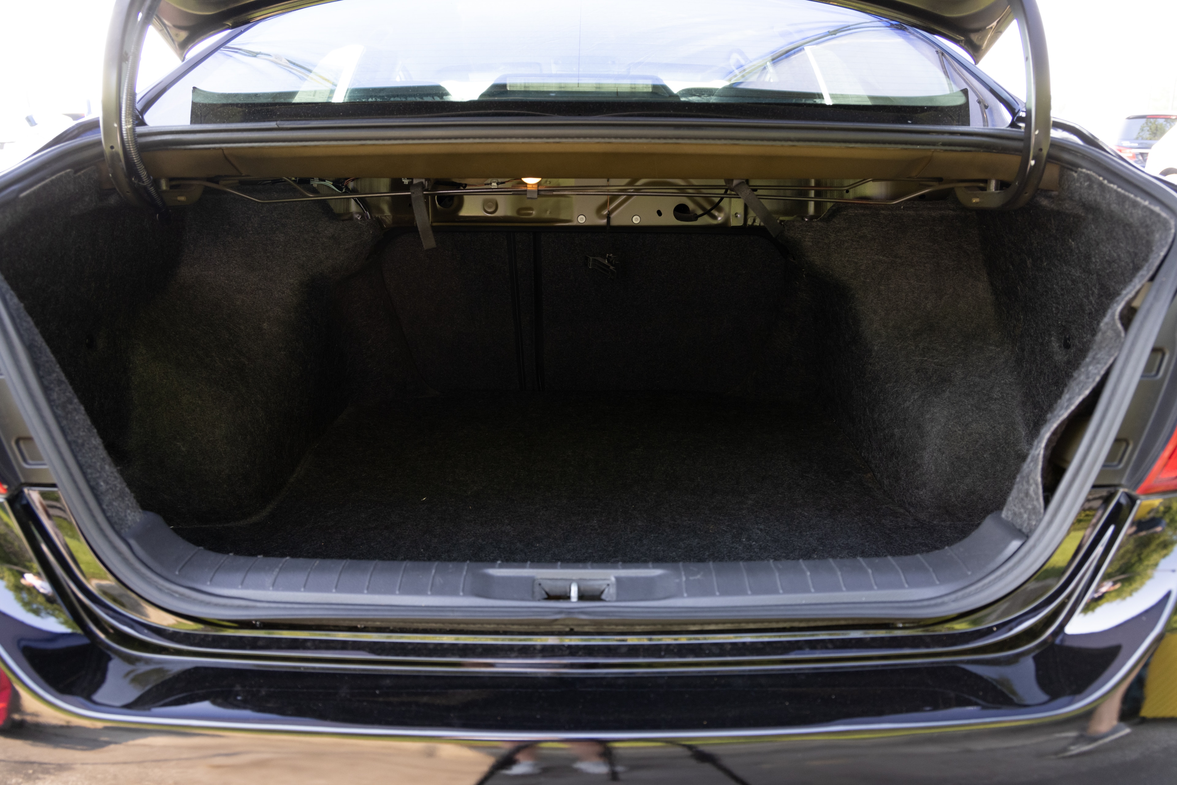 The trunk area is open giving a full view of the trunk area. A baby stroller, four grocery carriers, a yoga mat, and a set of golf clubs are placed inside.