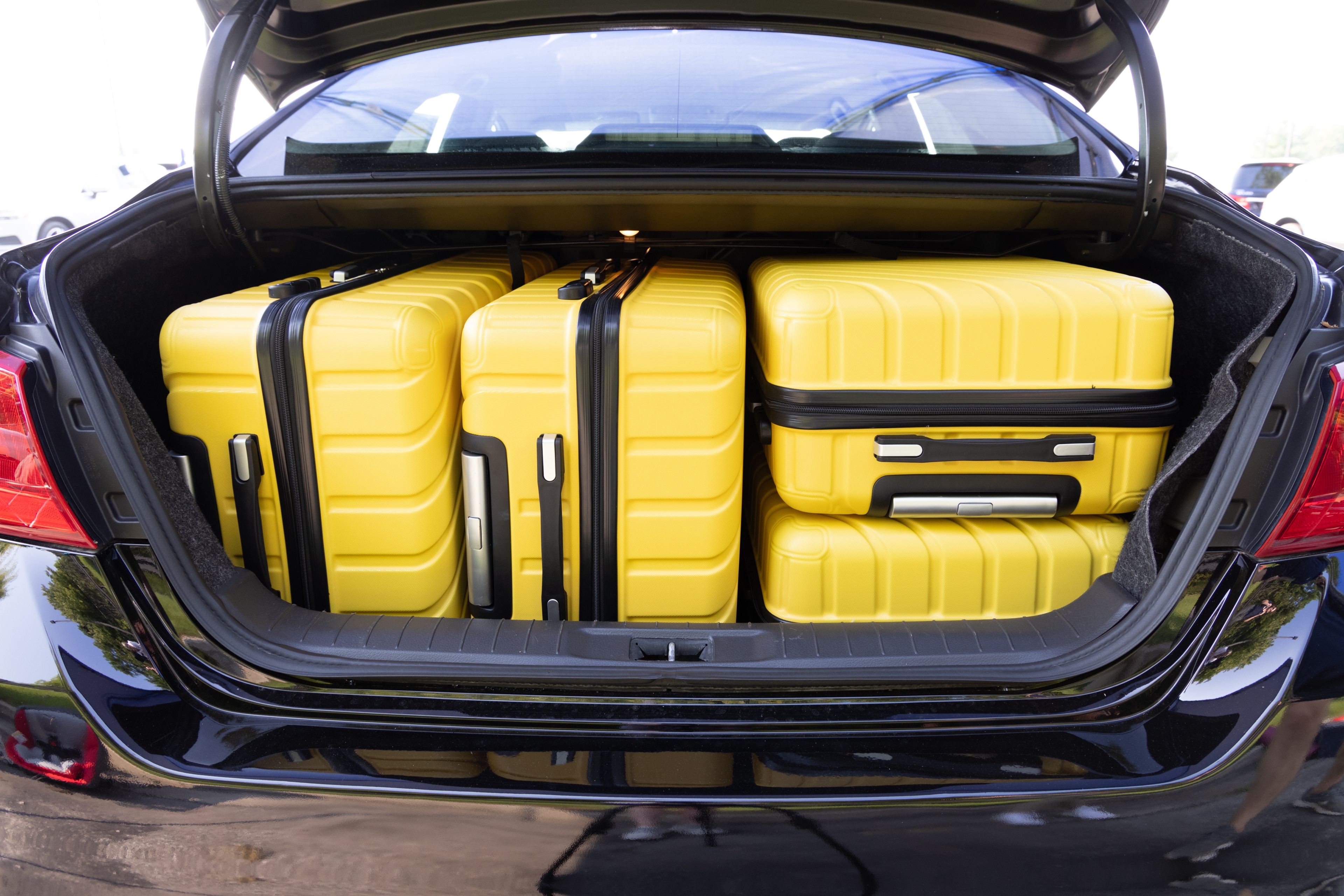 The trunk area is open giving a full view of the trunk area. Two large and two small suitcases are placed on their sides.
