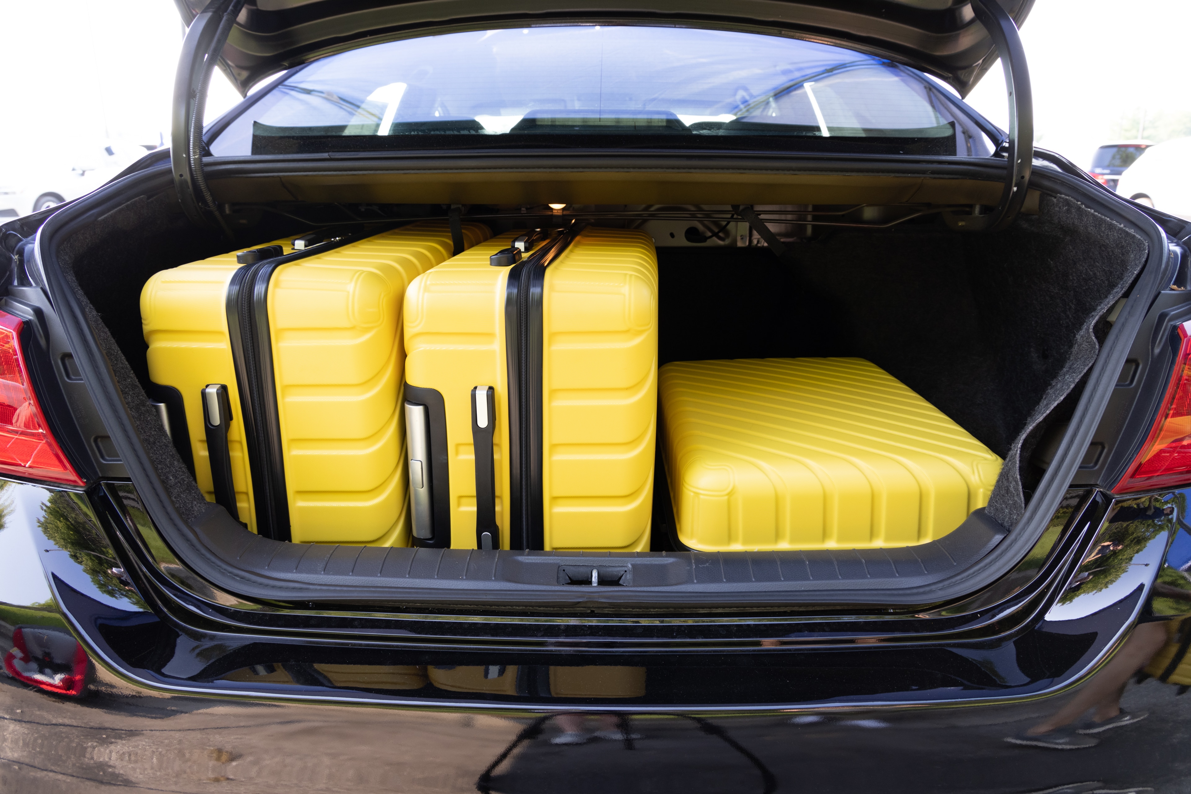 The trunk area is open giving a full view of the trunk area. Two large and two small suitcases are placed on their sides.