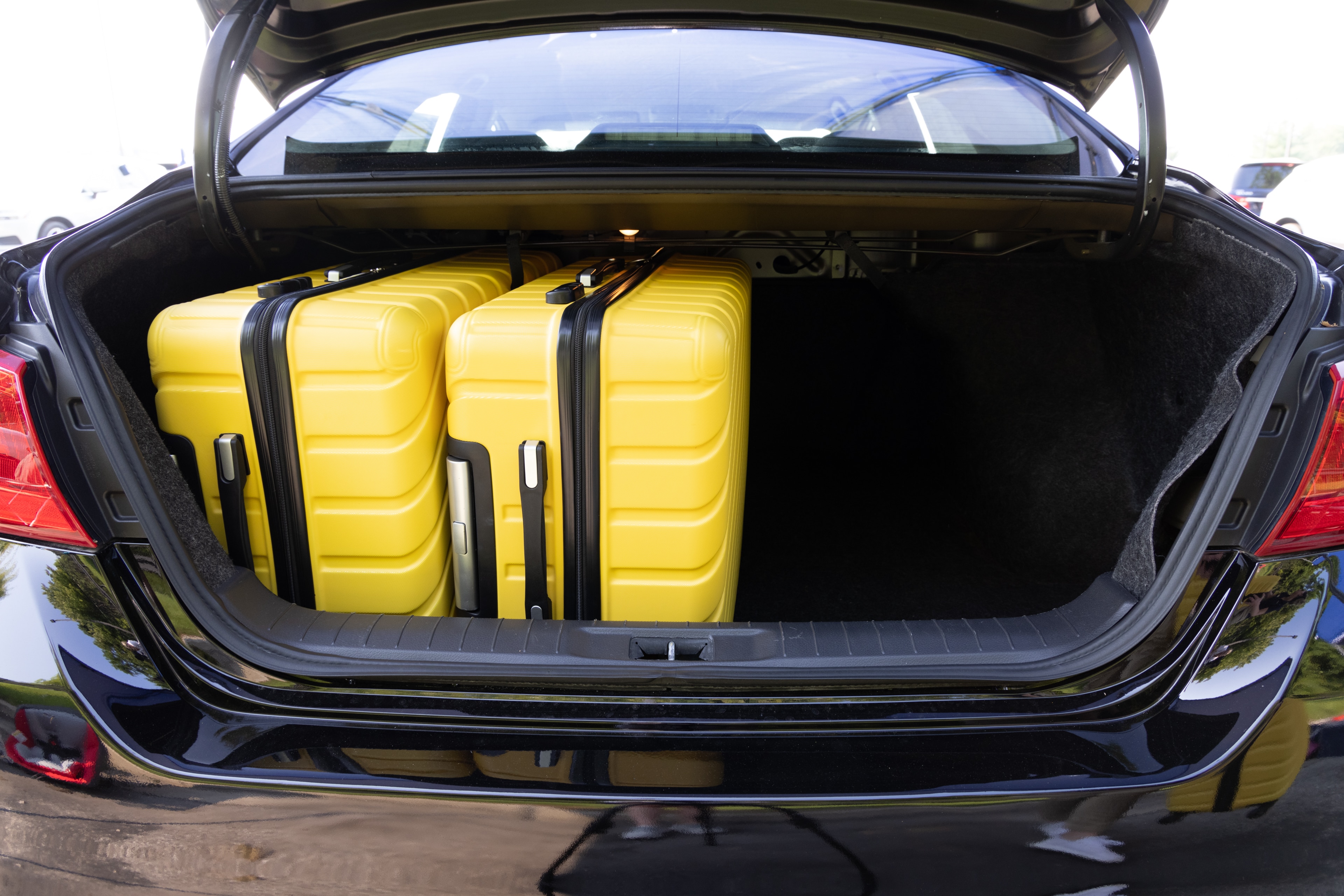 The trunk area is open giving a full view of the trunk area. Two large and two small suitcases are placed on their sides.