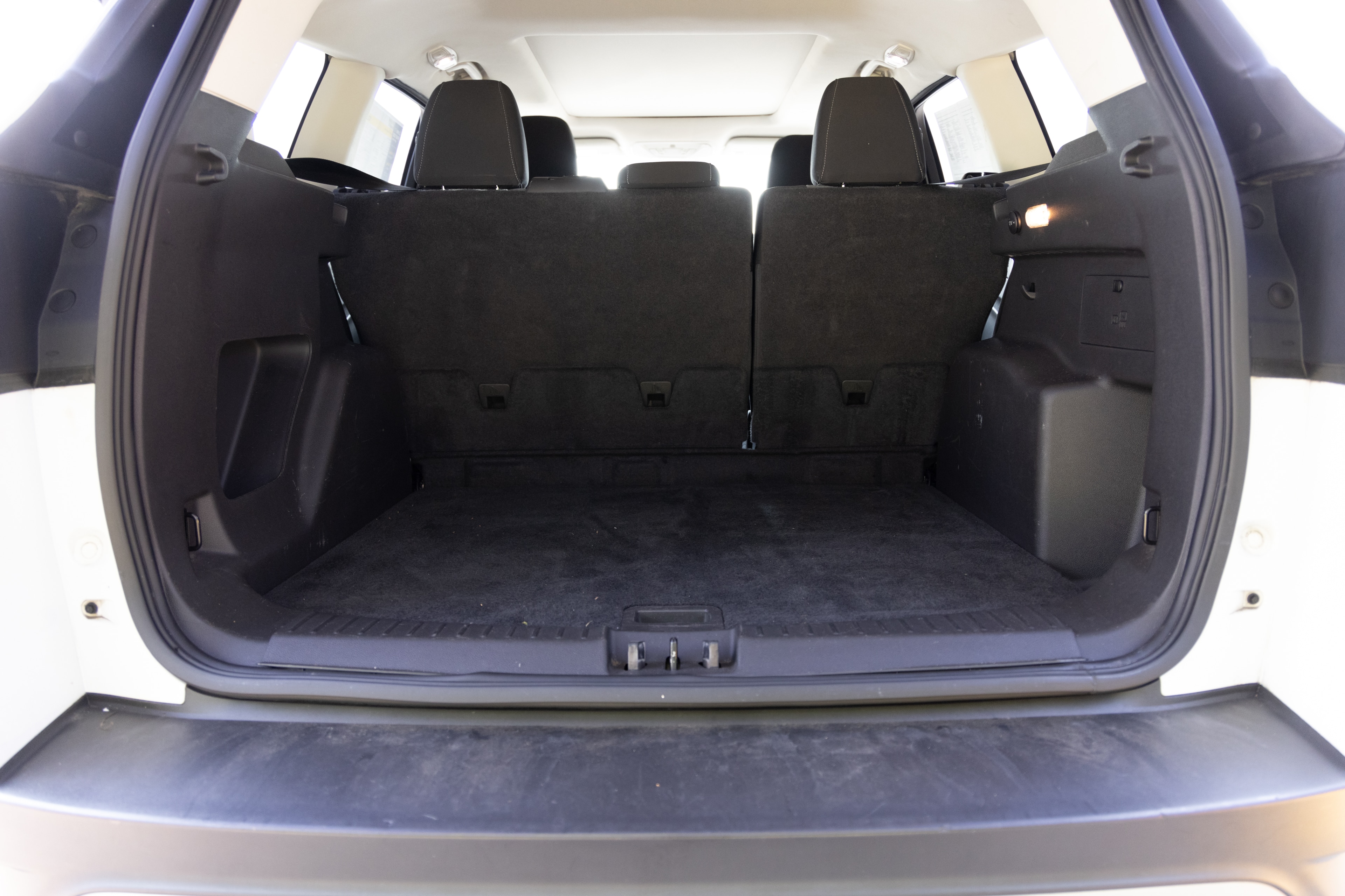 The cargo area is open giving a full view of the trunk area. A baby stroller, four grocery carriers, a yoga mat, and a set of golf clubs are placed inside.