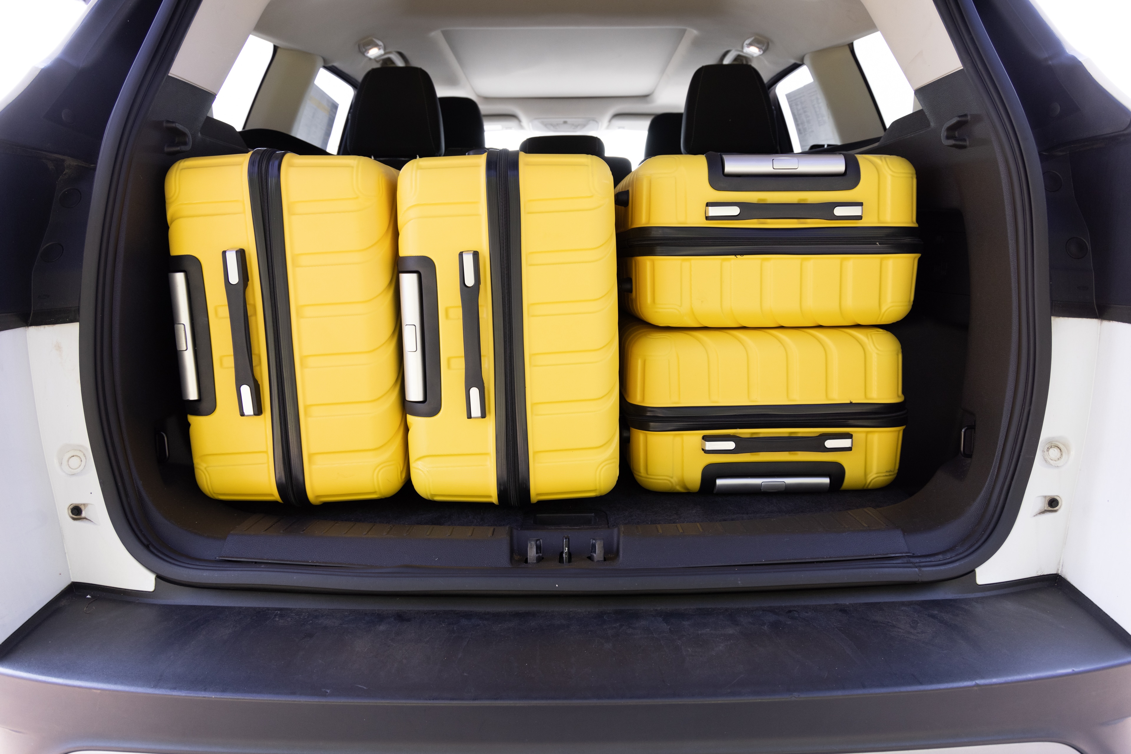 The cargo area is open giving a full view of the trunk area. Two large and two small suitcases are placed on their sides.