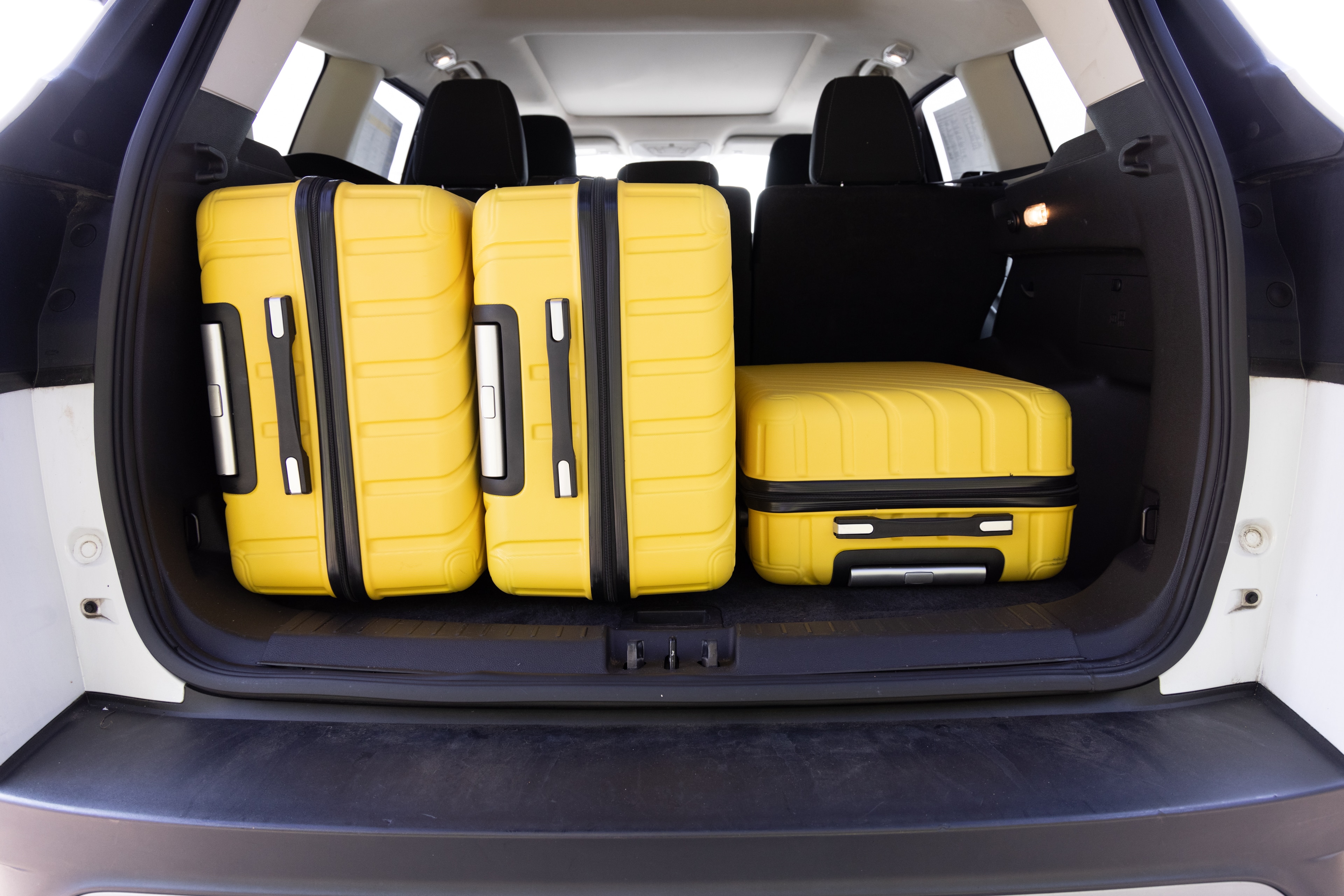 The cargo area is open giving a full view of the trunk area. Two large and two small suitcases are placed on their sides.