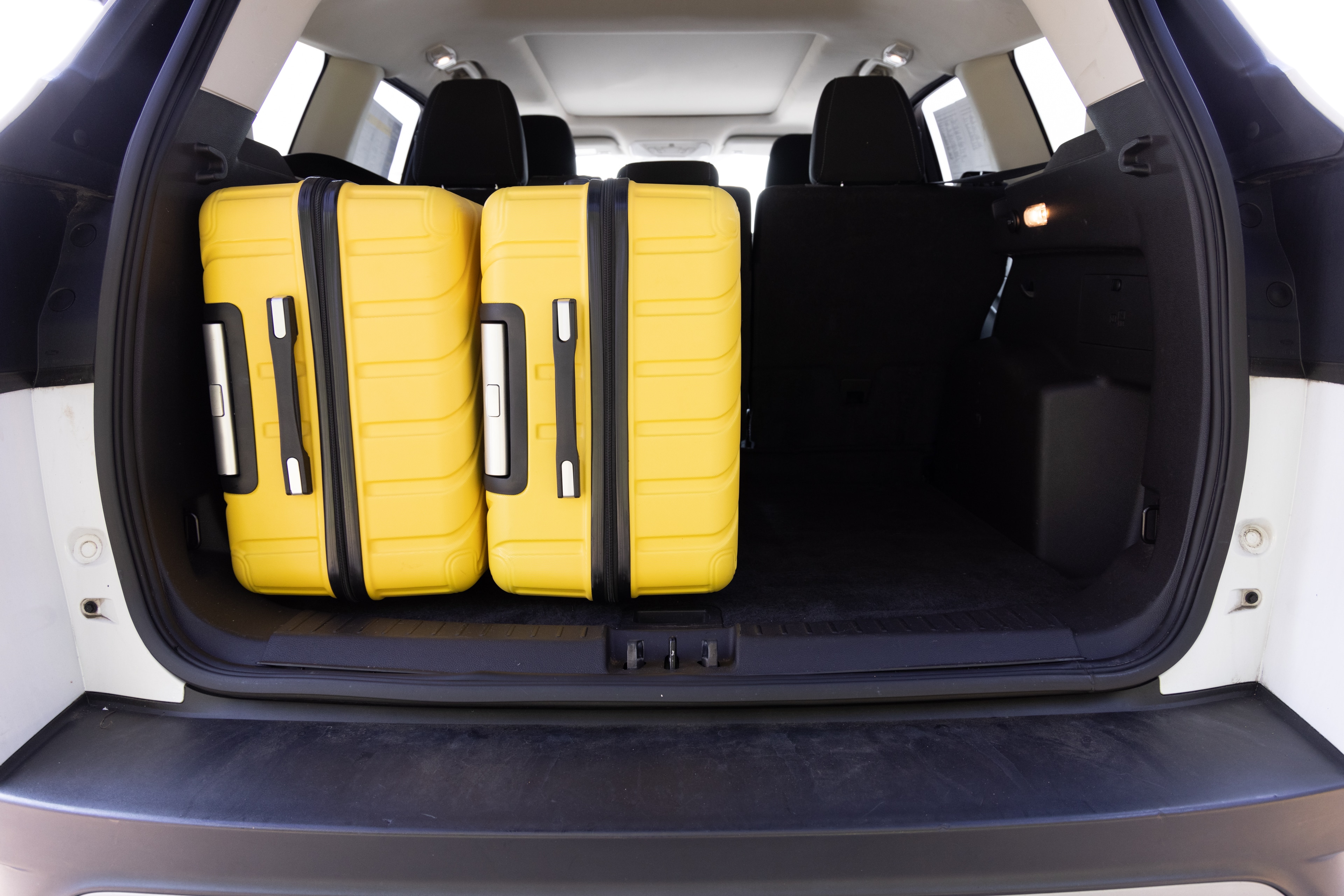 The cargo area is open giving a full view of the trunk area. Two large and two small suitcases are placed on their sides.