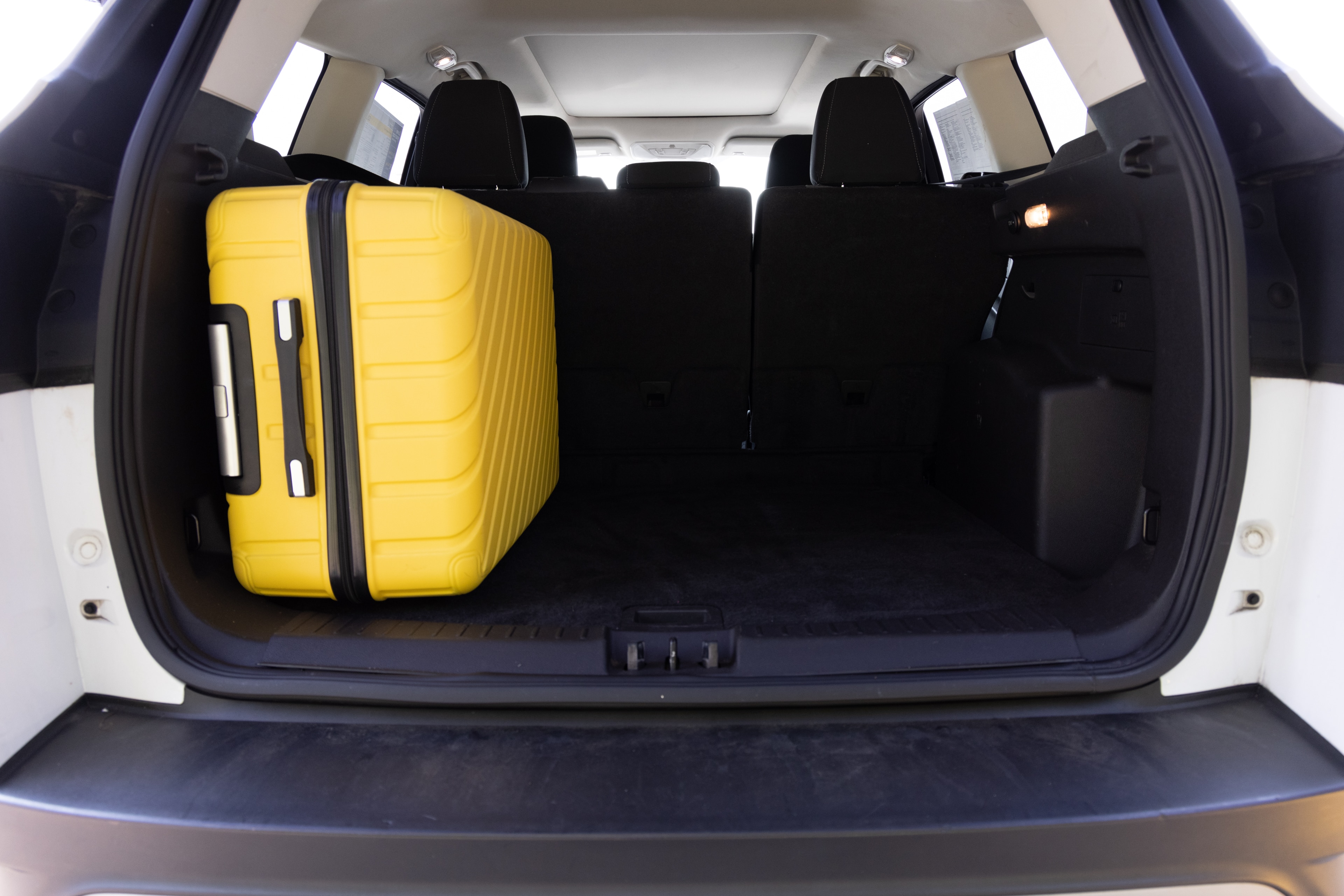 The cargo area is open giving a full view of the trunk area. Two large and two small suitcases are placed on their sides.