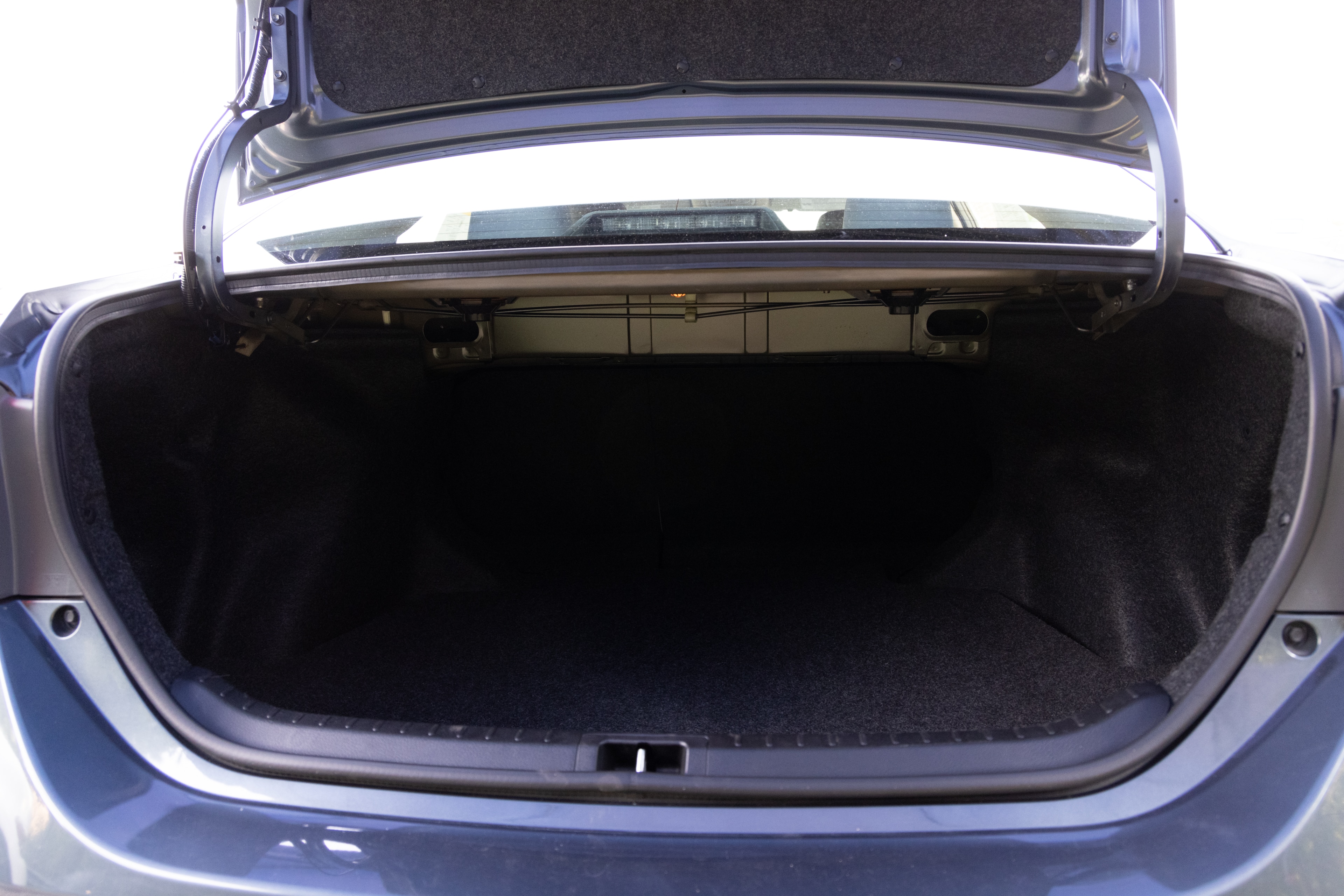 The trunk area is open giving a full view of the trunk area. A baby stroller, four grocery carriers, a yoga mat, and a set of golf clubs are placed inside.