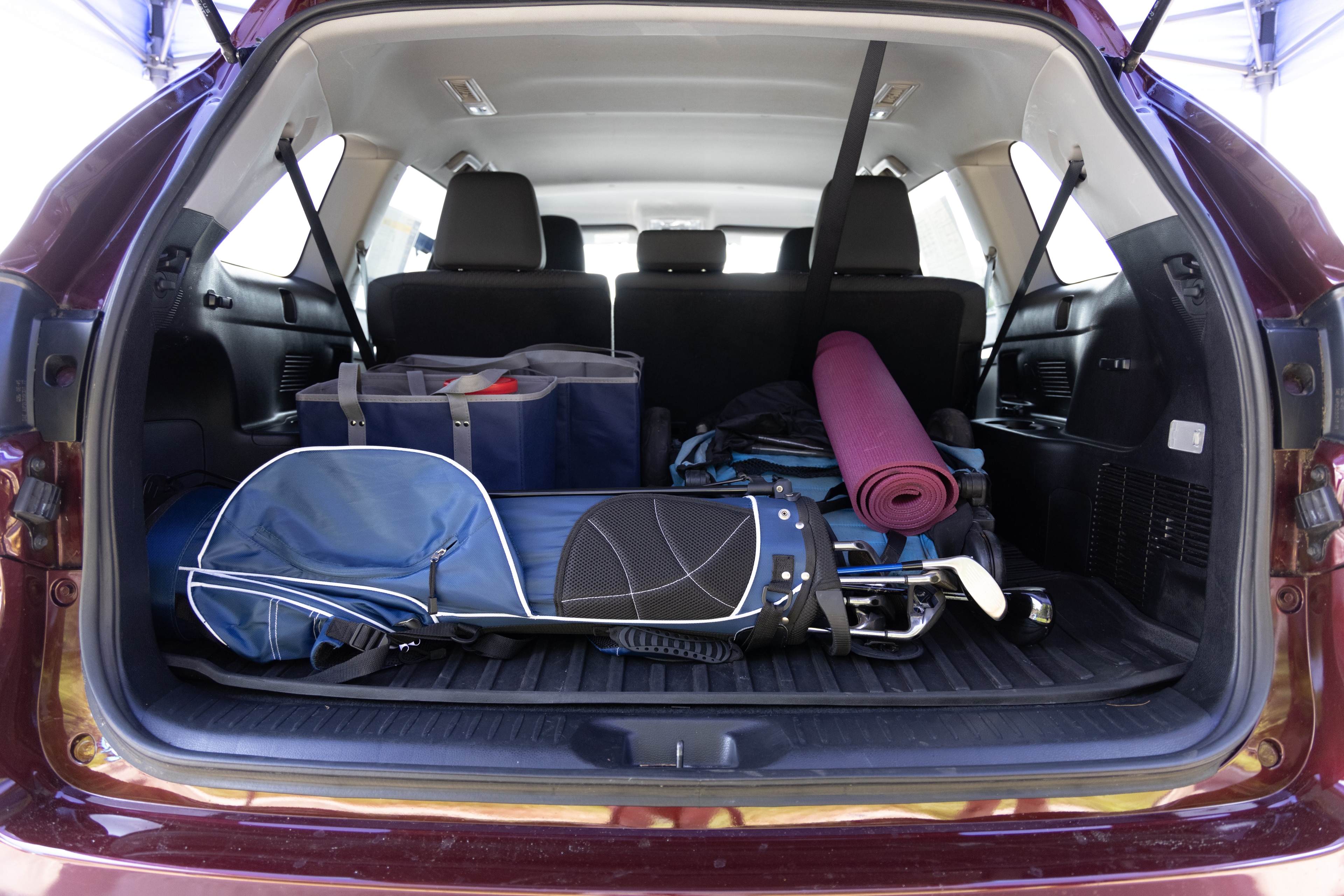 The cargo area is open giving a full view of the cargo area. A baby stroller, four grocery carriers, a yoga mat, and a set of golf clubs are placed inside.