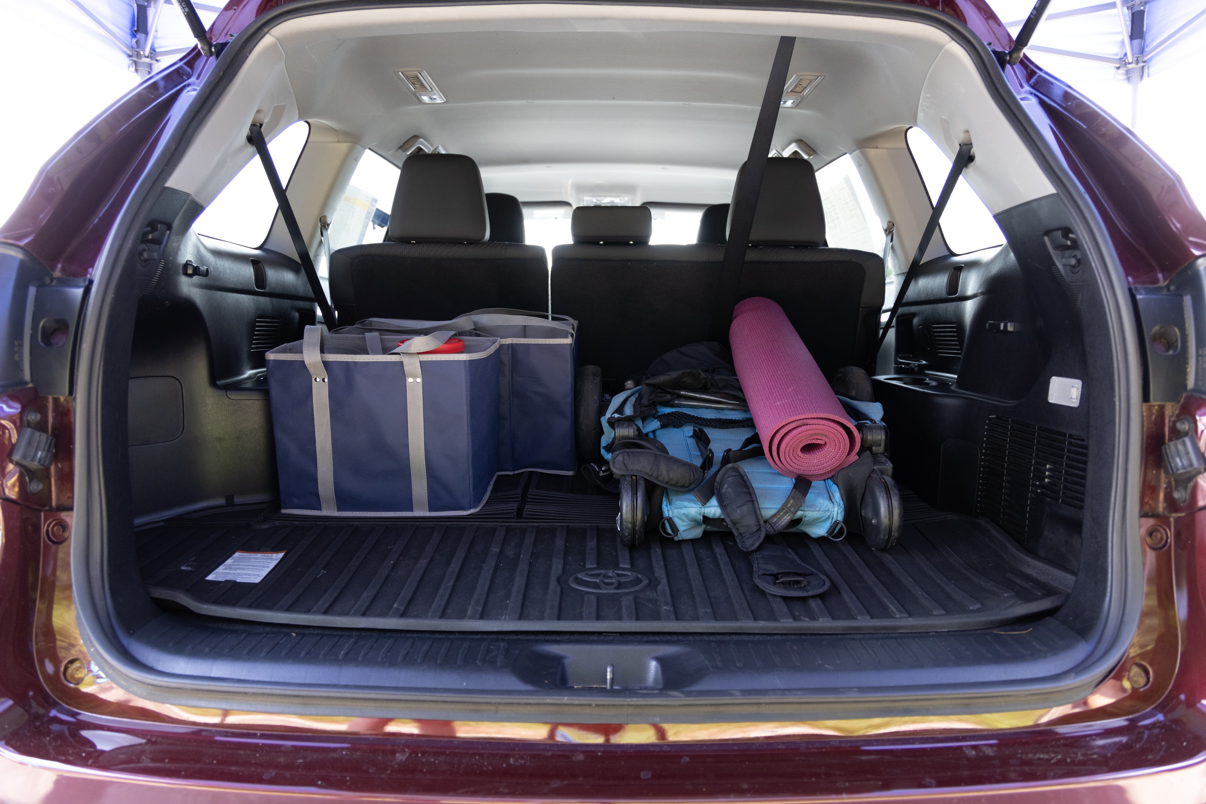 The cargo area is open giving a full view of the cargo area. A baby stroller, four grocery carriers, a yoga mat, and a set of golf clubs are placed inside.
