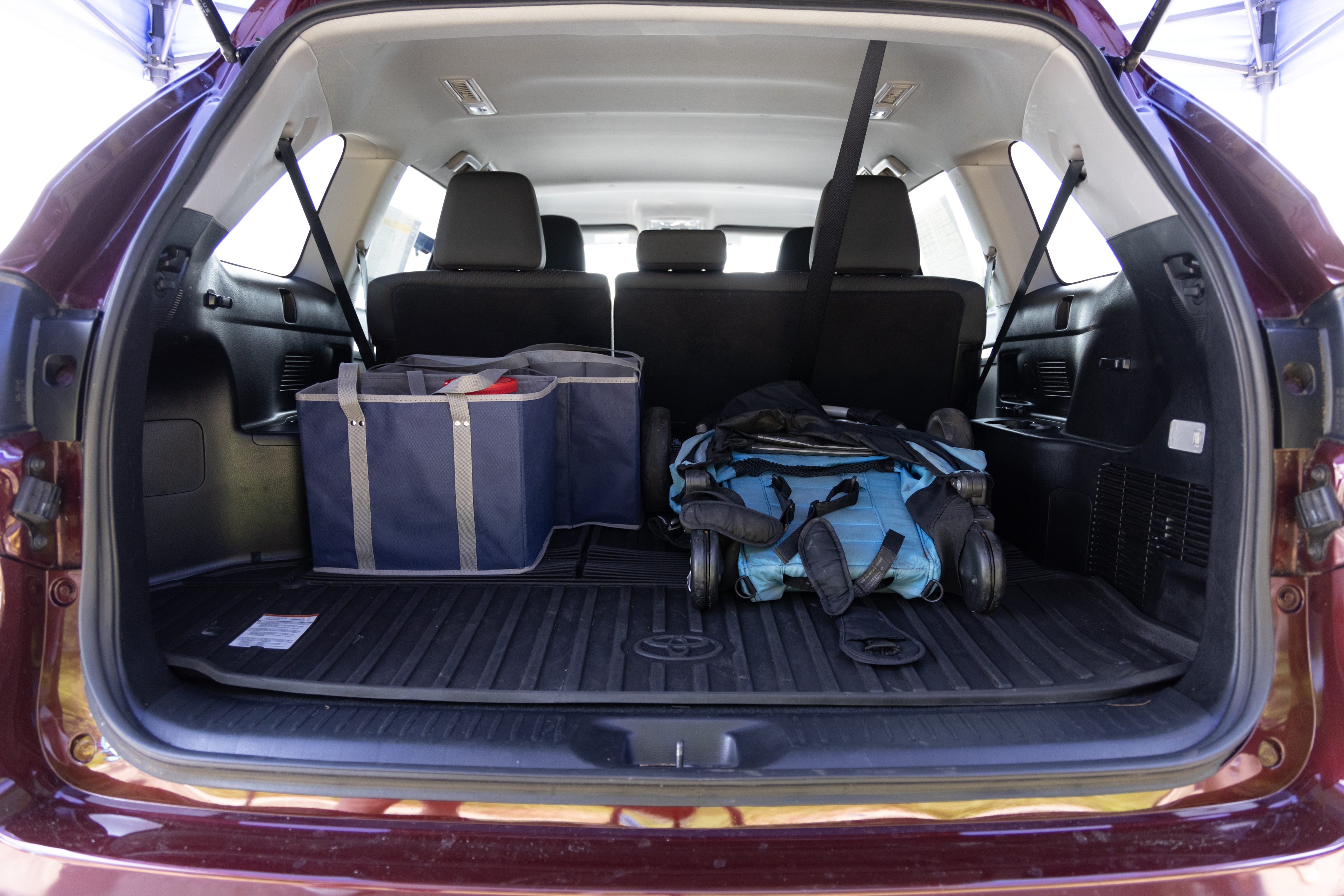 The cargo area is open giving a full view of the cargo area. A baby stroller, four grocery carriers, a yoga mat, and a set of golf clubs are placed inside.