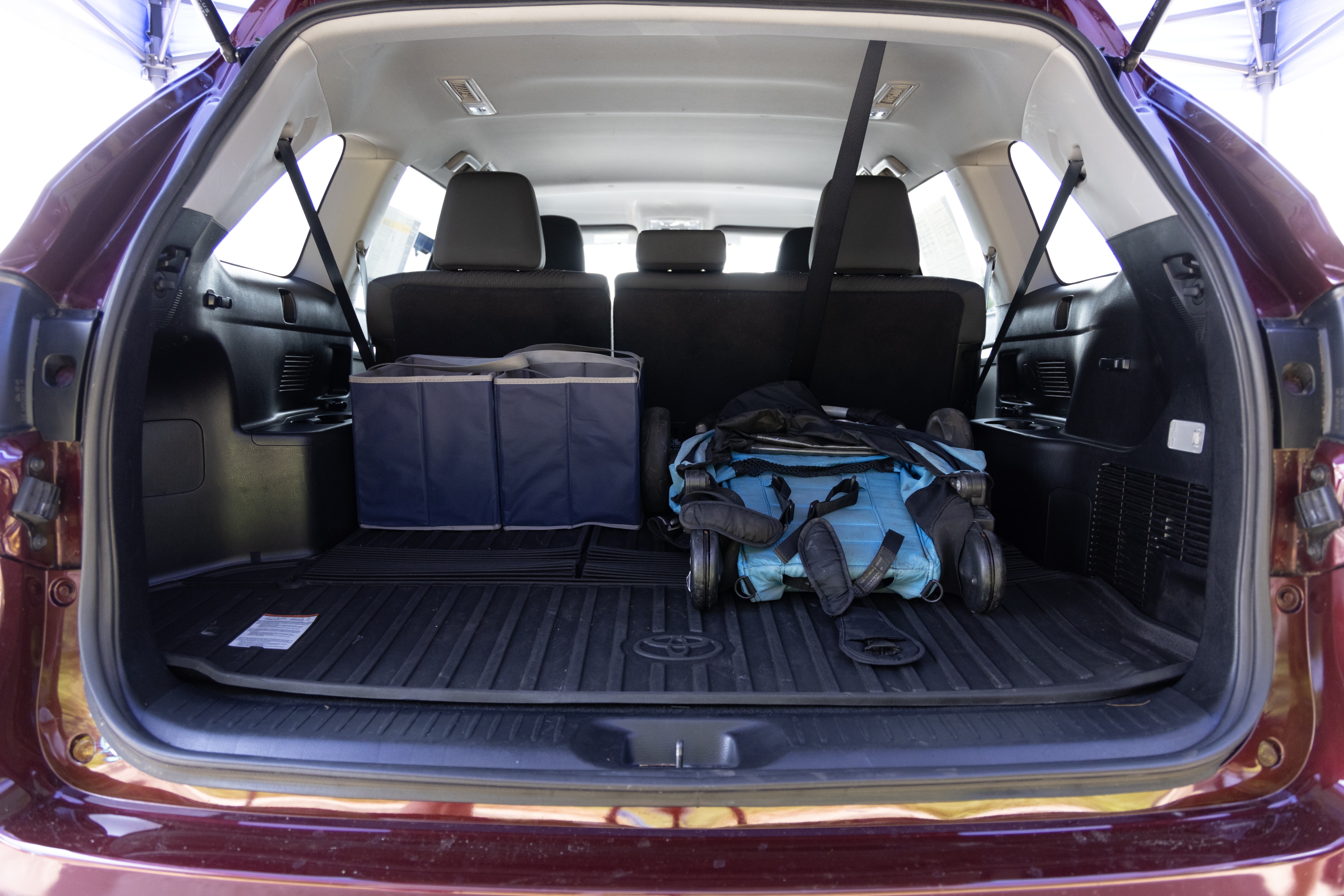 The cargo area is open giving a full view of the cargo area. A baby stroller, four grocery carriers, a yoga mat, and a set of golf clubs are placed inside.