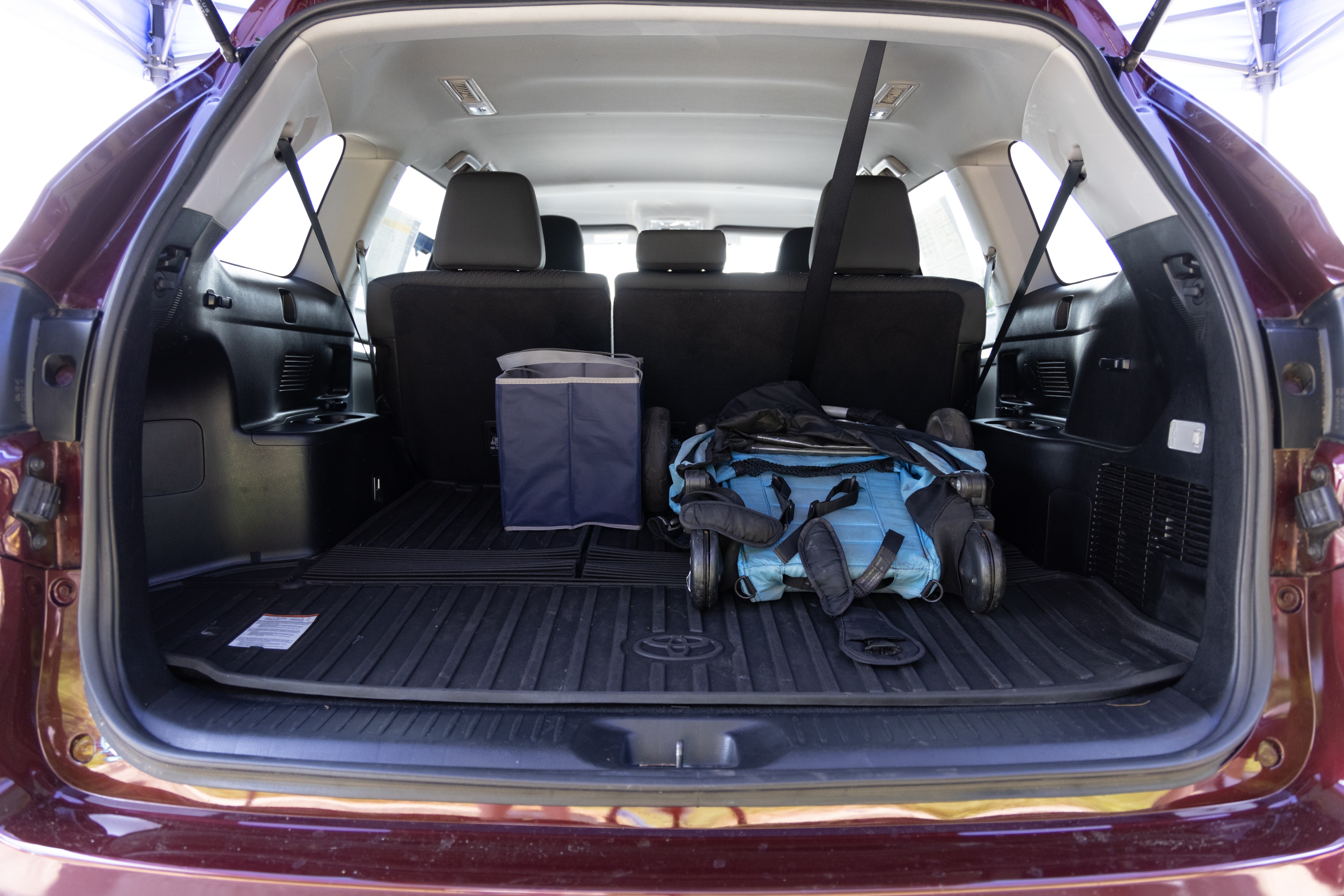 The cargo area is open giving a full view of the cargo area. A baby stroller, four grocery carriers, a yoga mat, and a set of golf clubs are placed inside.