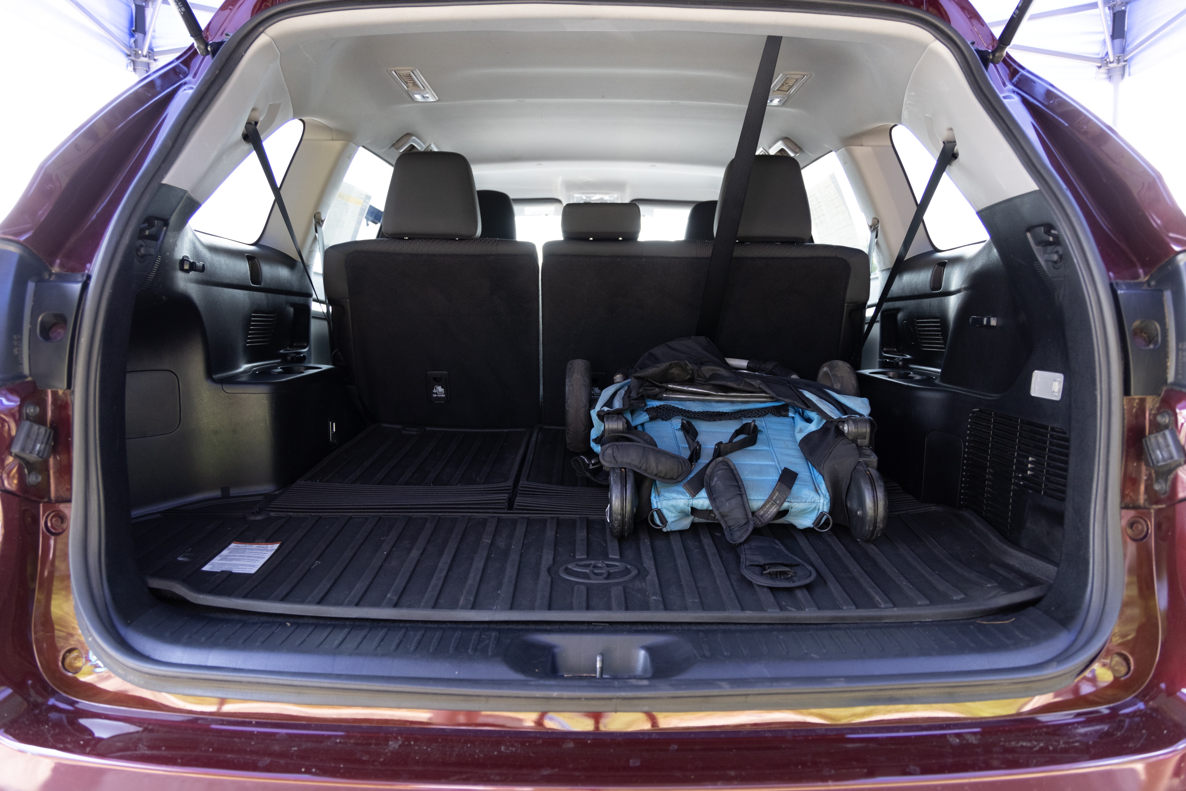 The cargo area is open giving a full view of the cargo area. A baby stroller, four grocery carriers, a yoga mat, and a set of golf clubs are placed inside.
