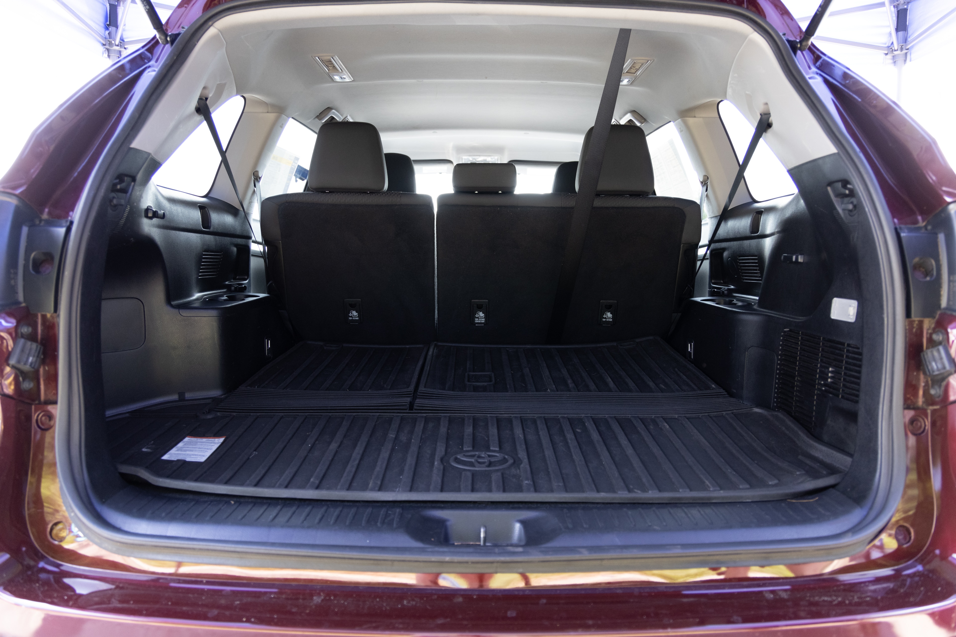 The cargo area is open giving a full view of the cargo area. A baby stroller, four grocery carriers, a yoga mat, and a set of golf clubs are placed inside.