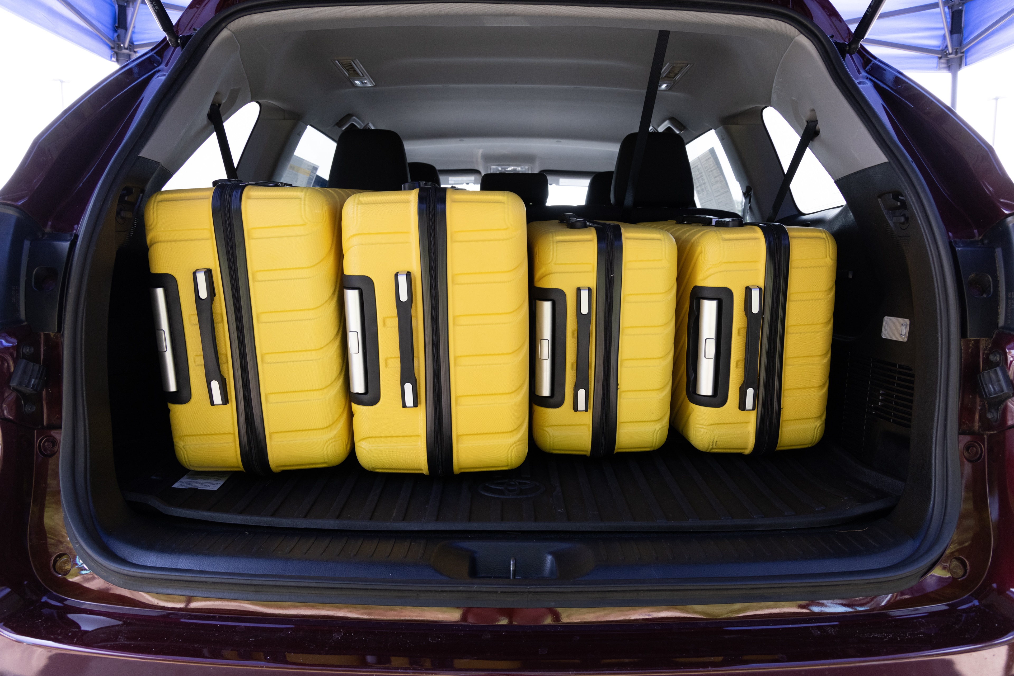 The cargo area is open giving a full view of the cargo area. Two large and two small suitcases are placed on their sides.