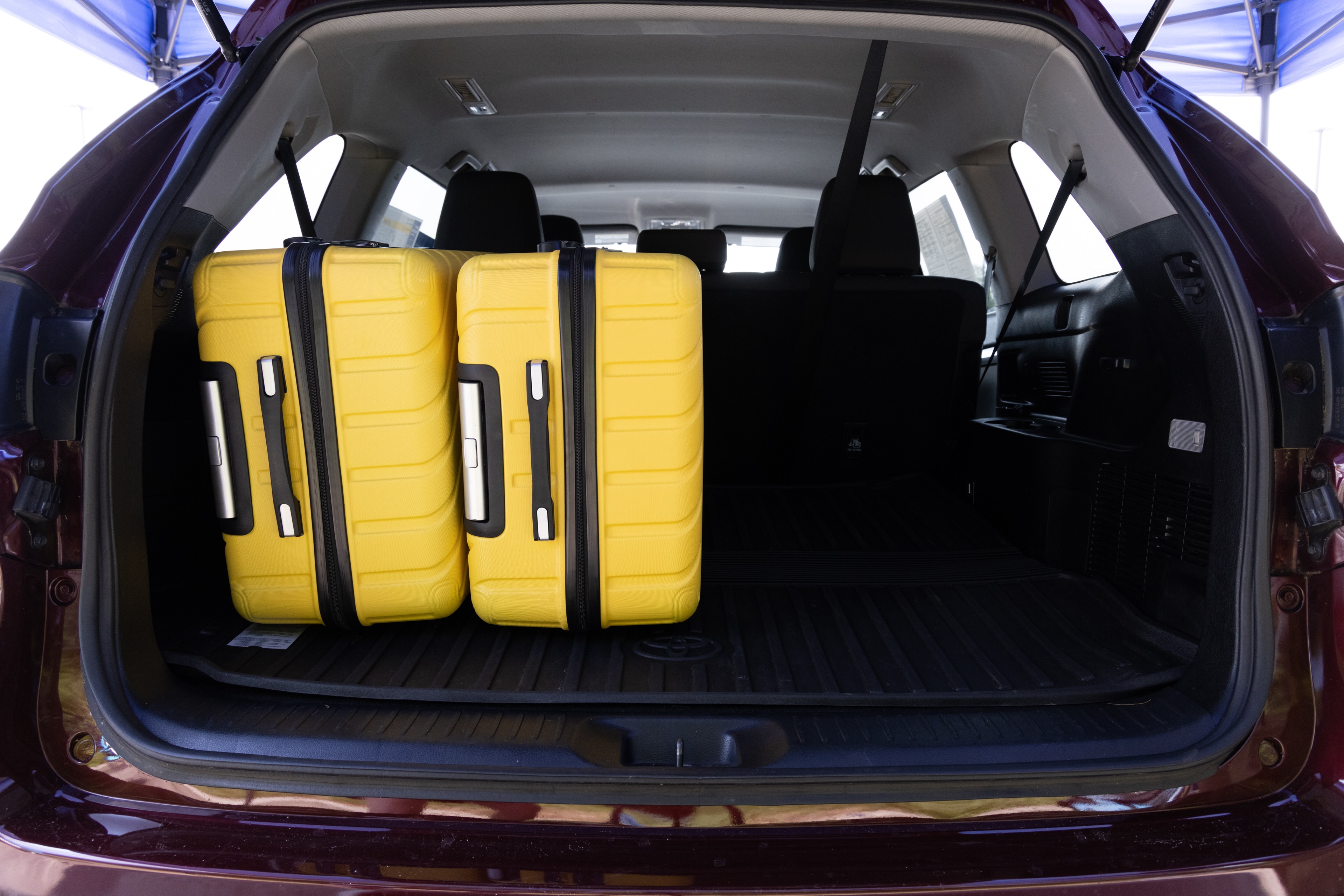 The cargo area is open giving a full view of the cargo area. Two large and two small suitcases are placed on their sides.