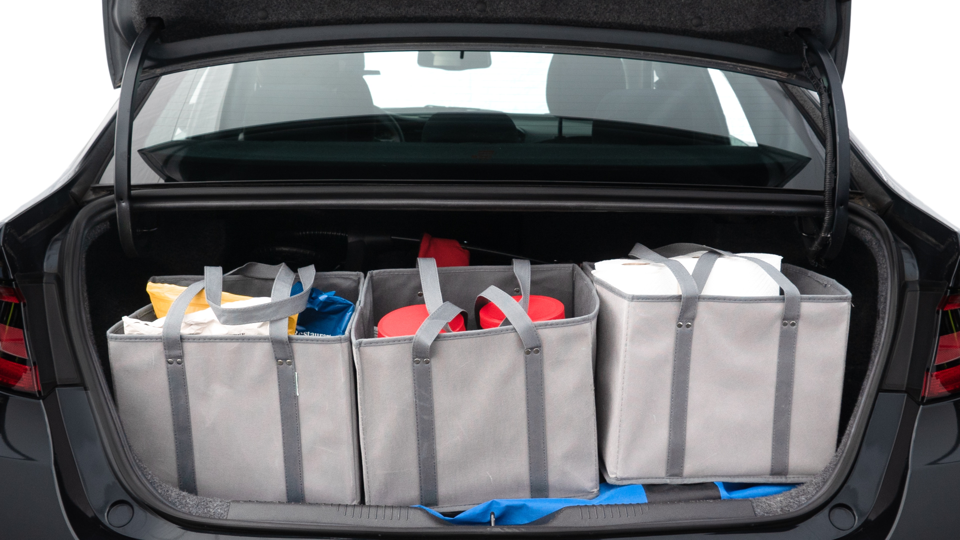 The trunk lid is open showing full view of the trunk. A baby stroller, three grocery carriers, two camping chairs in the carrying bag, and a set of golf clubs are placed inside.