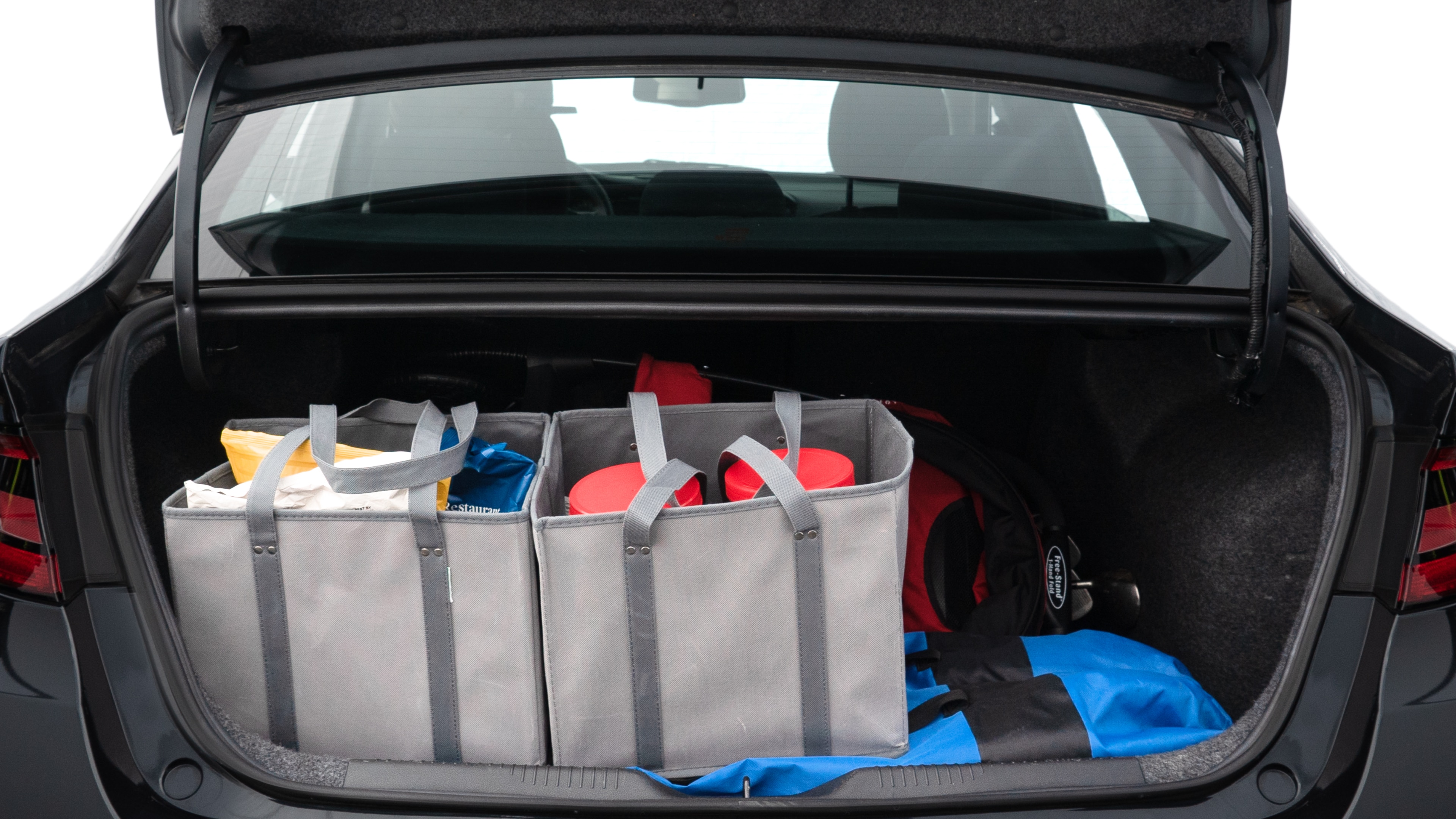 The trunk lid is open showing full view of the trunk. A baby stroller, three grocery carriers, two camping chairs in the carrying bag, and a set of golf clubs are placed inside.