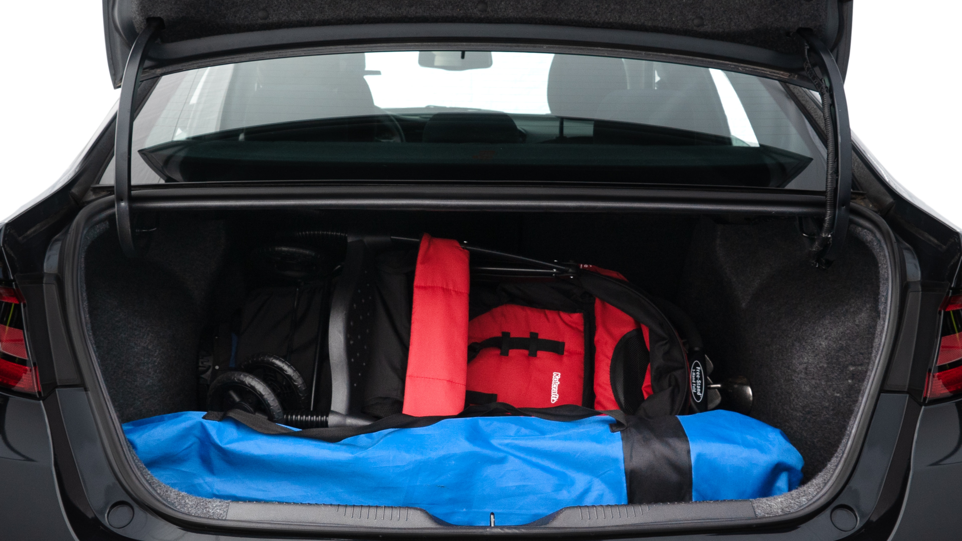 The trunk lid is open showing full view of the trunk. A baby stroller, three grocery carriers, two camping chairs in the carrying bag, and a set of golf clubs are placed inside.