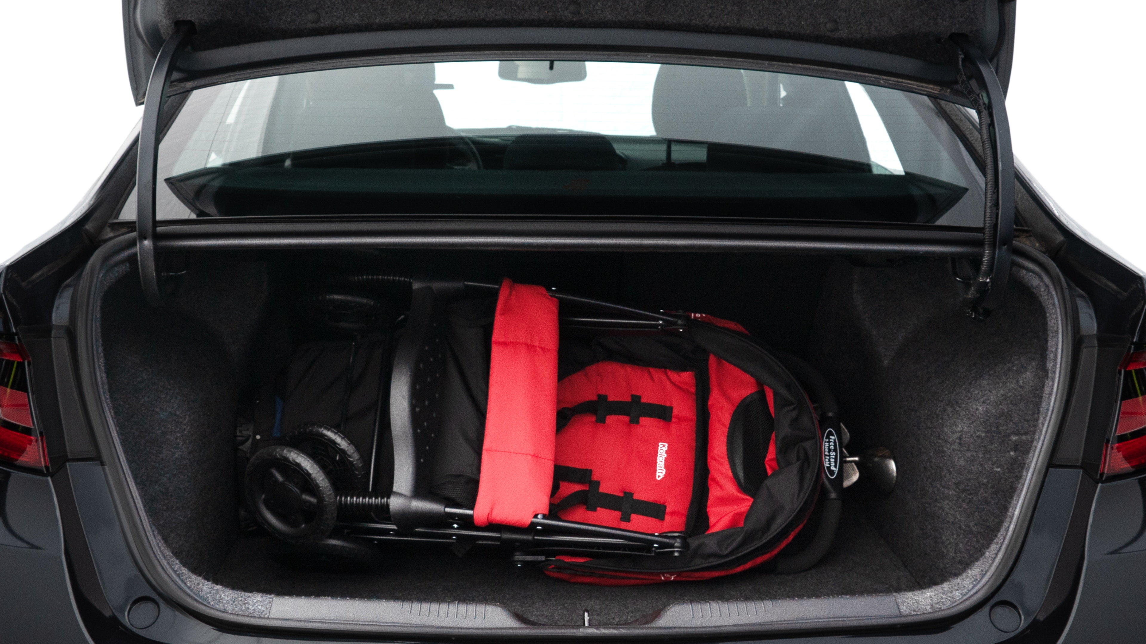The trunk lid is open showing full view of the trunk. A baby stroller, three grocery carriers, two camping chairs in the carrying bag, and a set of golf clubs are placed inside.