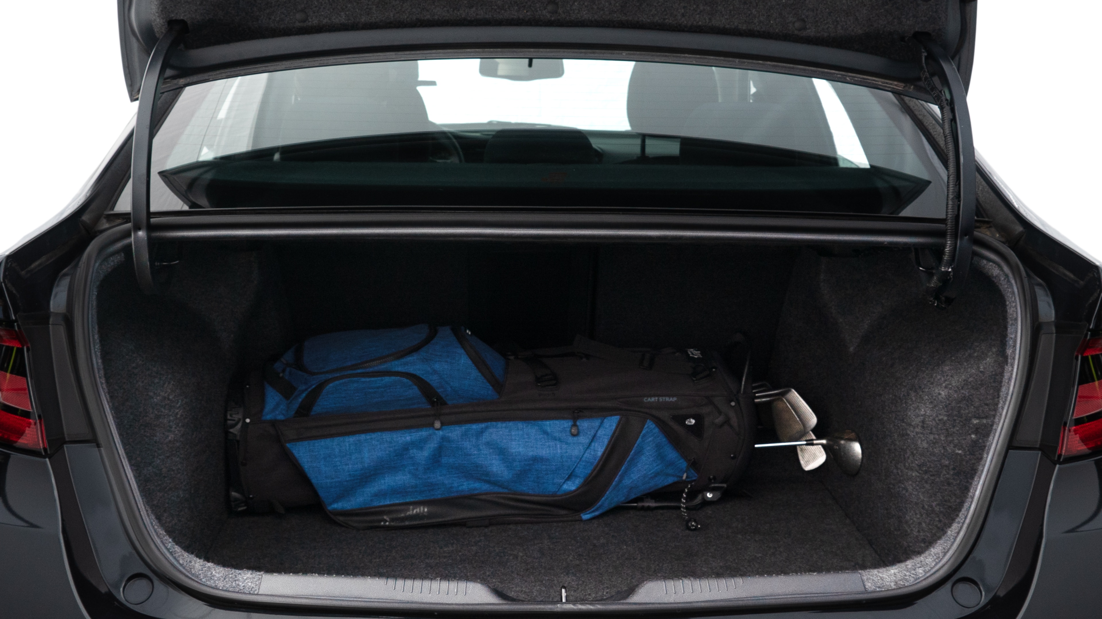 The trunk lid is open showing full view of the trunk. A baby stroller, three grocery carriers, two camping chairs in the carrying bag, and a set of golf clubs are placed inside.