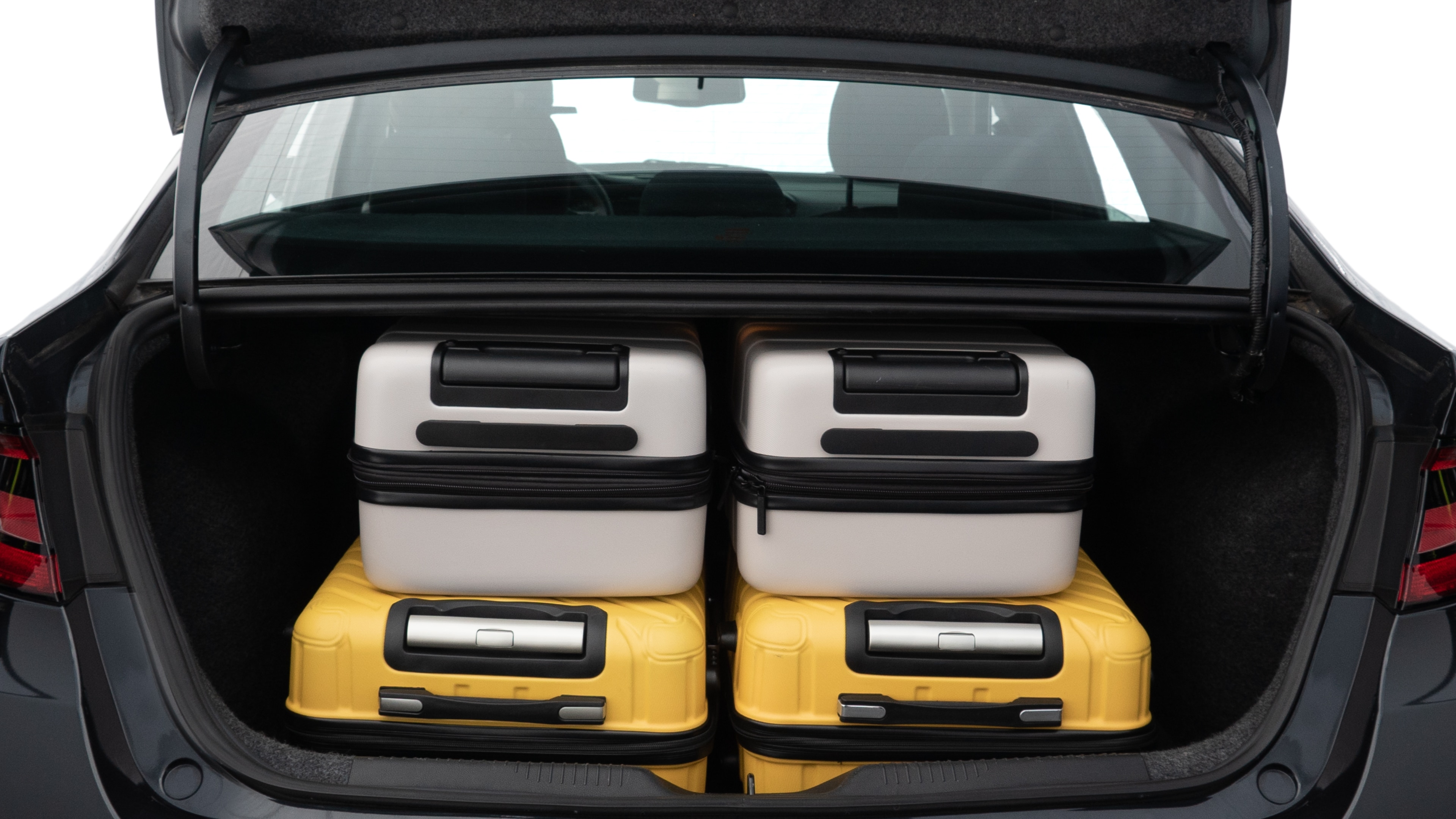 The trunk lid is open, showing full view of the trunk space. Two medium and two small suitcases are placed inside.