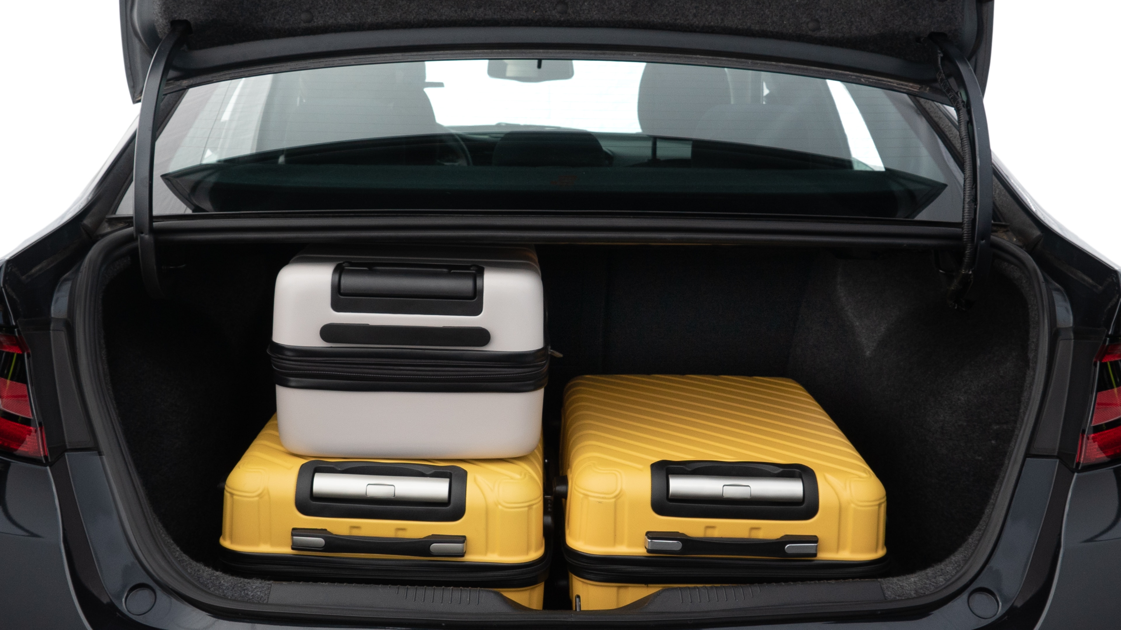 The trunk lid is open, showing full view of the trunk space. Two medium and two small suitcases are placed inside.