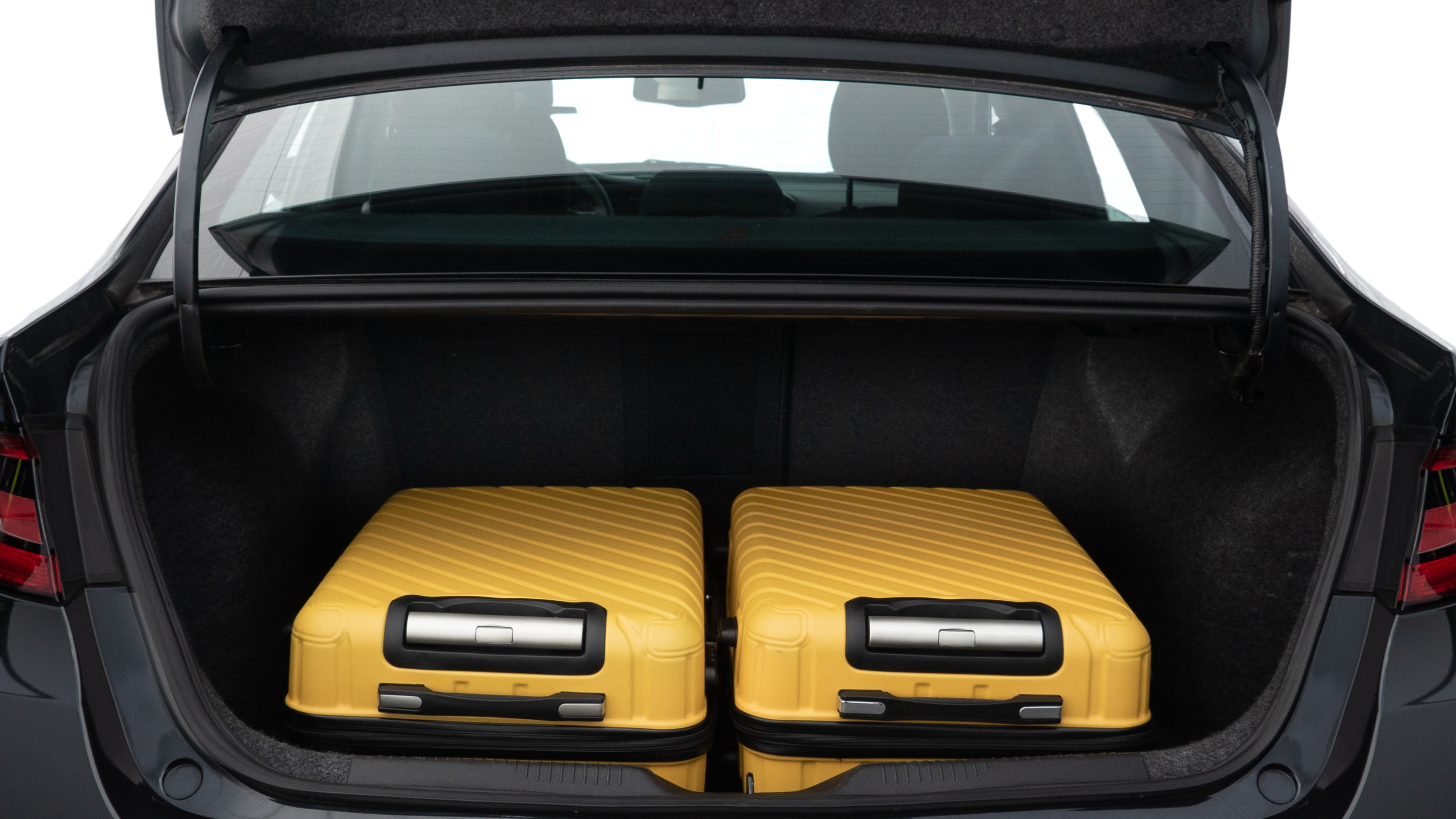 The trunk lid is open, showing full view of the trunk space. Two medium and two small suitcases are placed inside.