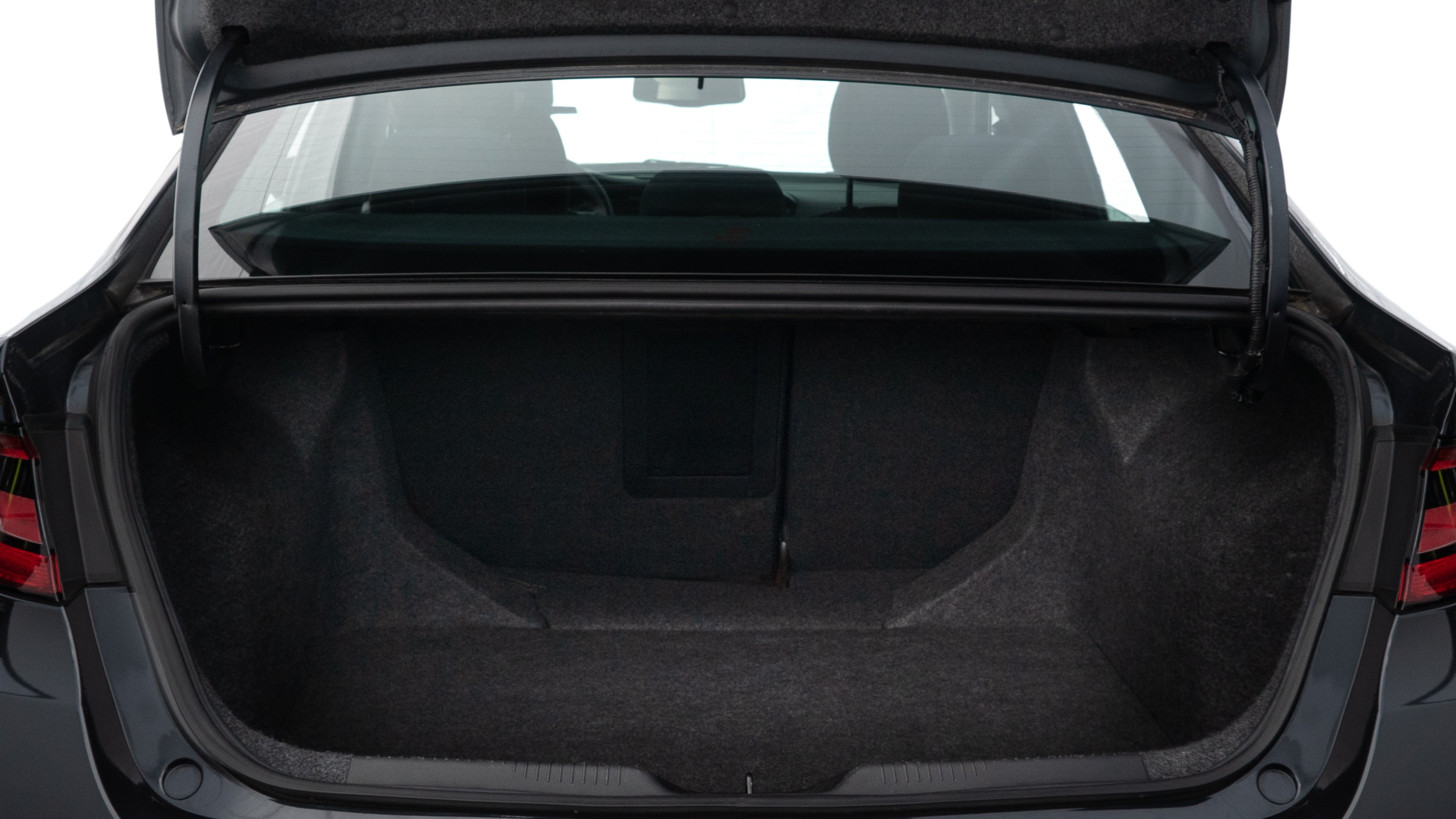 The trunk lid is open, showing full view of the trunk space. Two medium and two small suitcases are placed inside.