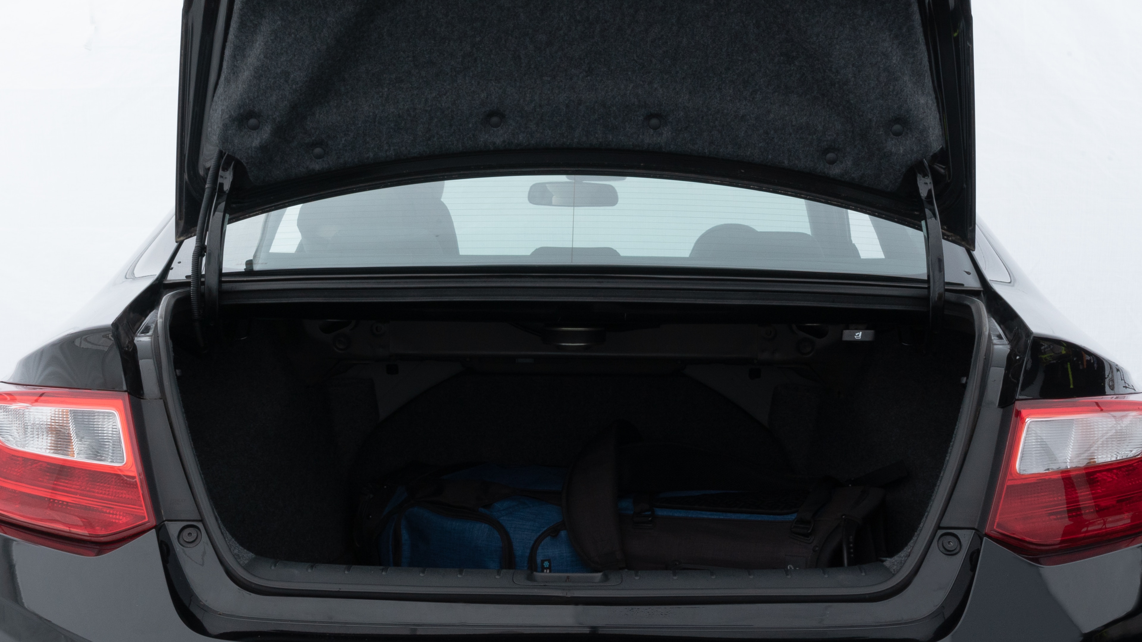 The trunk lid is open showing full view of the trunk. A baby stroller, three grocery carriers, two camping chairs in the carrying bag, and a set of golf clubs are placed inside.