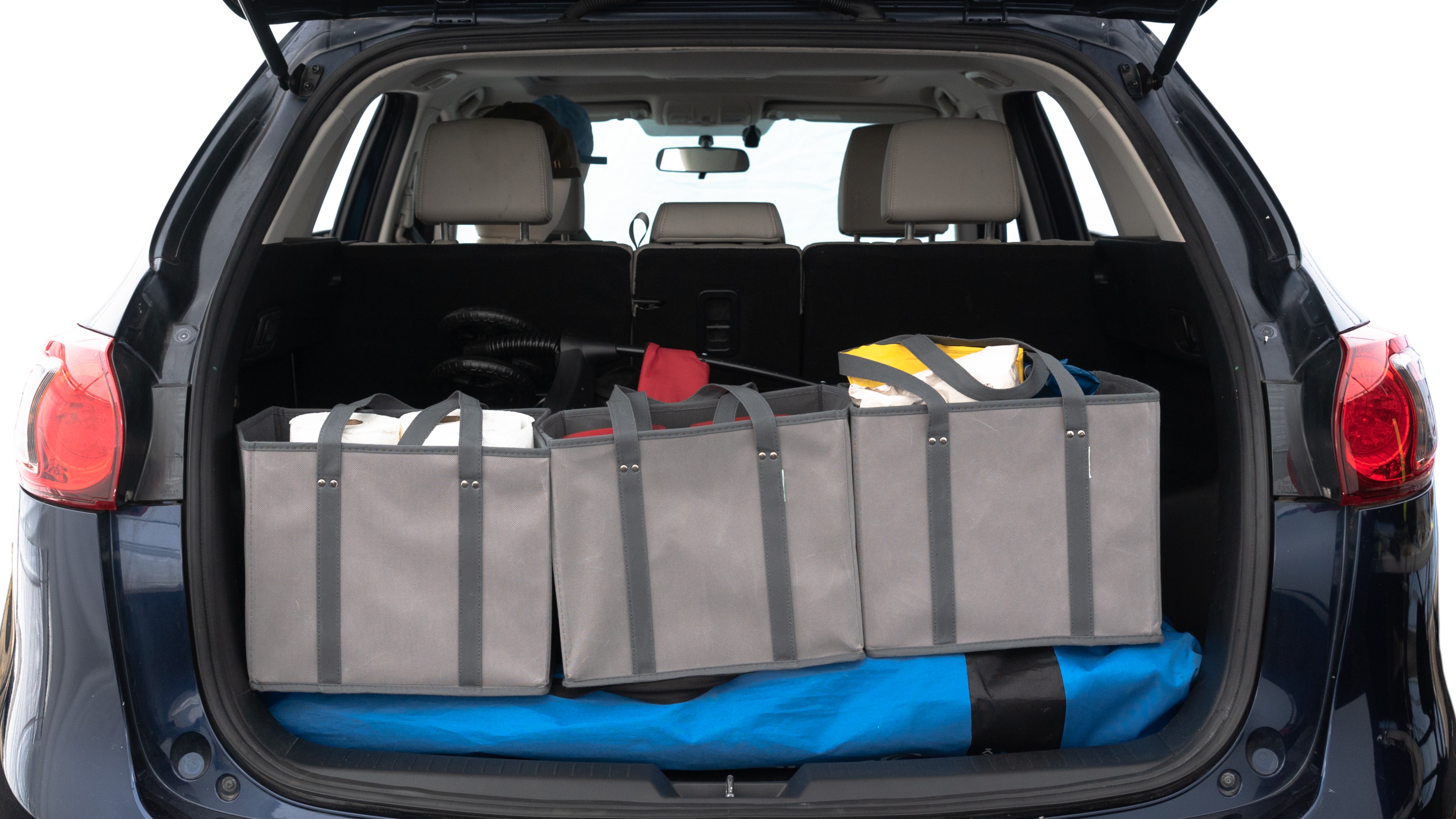 The trunk lid is open showing full view of the trunk. A baby stroller, three grocery carriers, two camping chairs in the carrying bag, and a set of golf clubs are placed inside.
