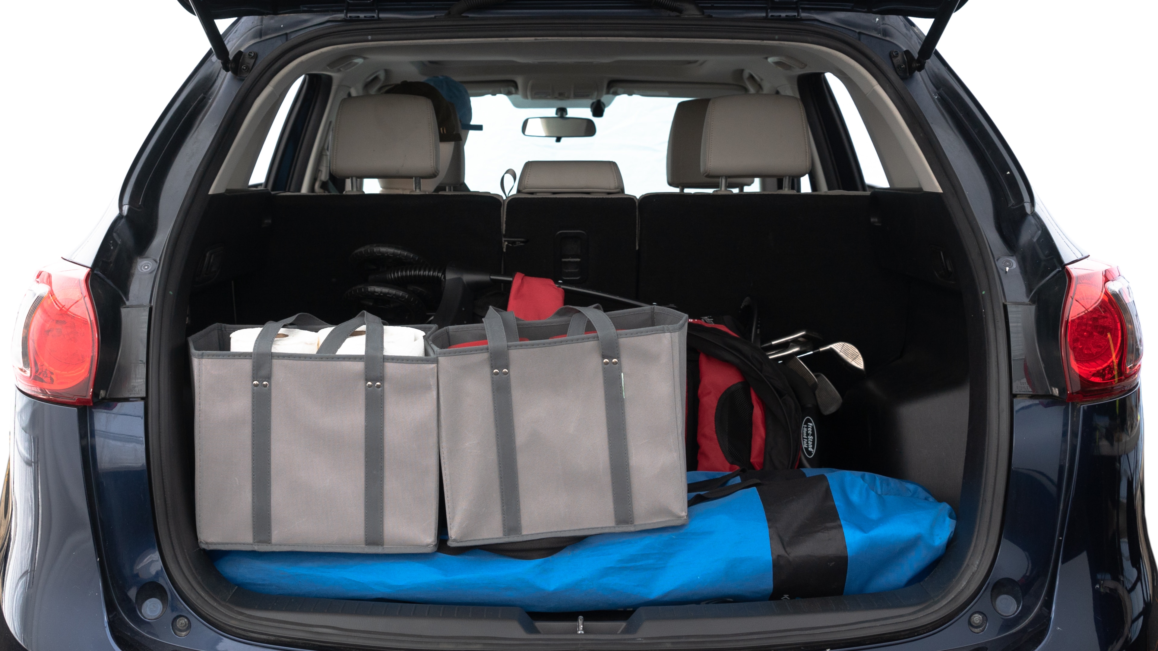 The trunk lid is open showing full view of the trunk. A baby stroller, three grocery carriers, two camping chairs in the carrying bag, and a set of golf clubs are placed inside.