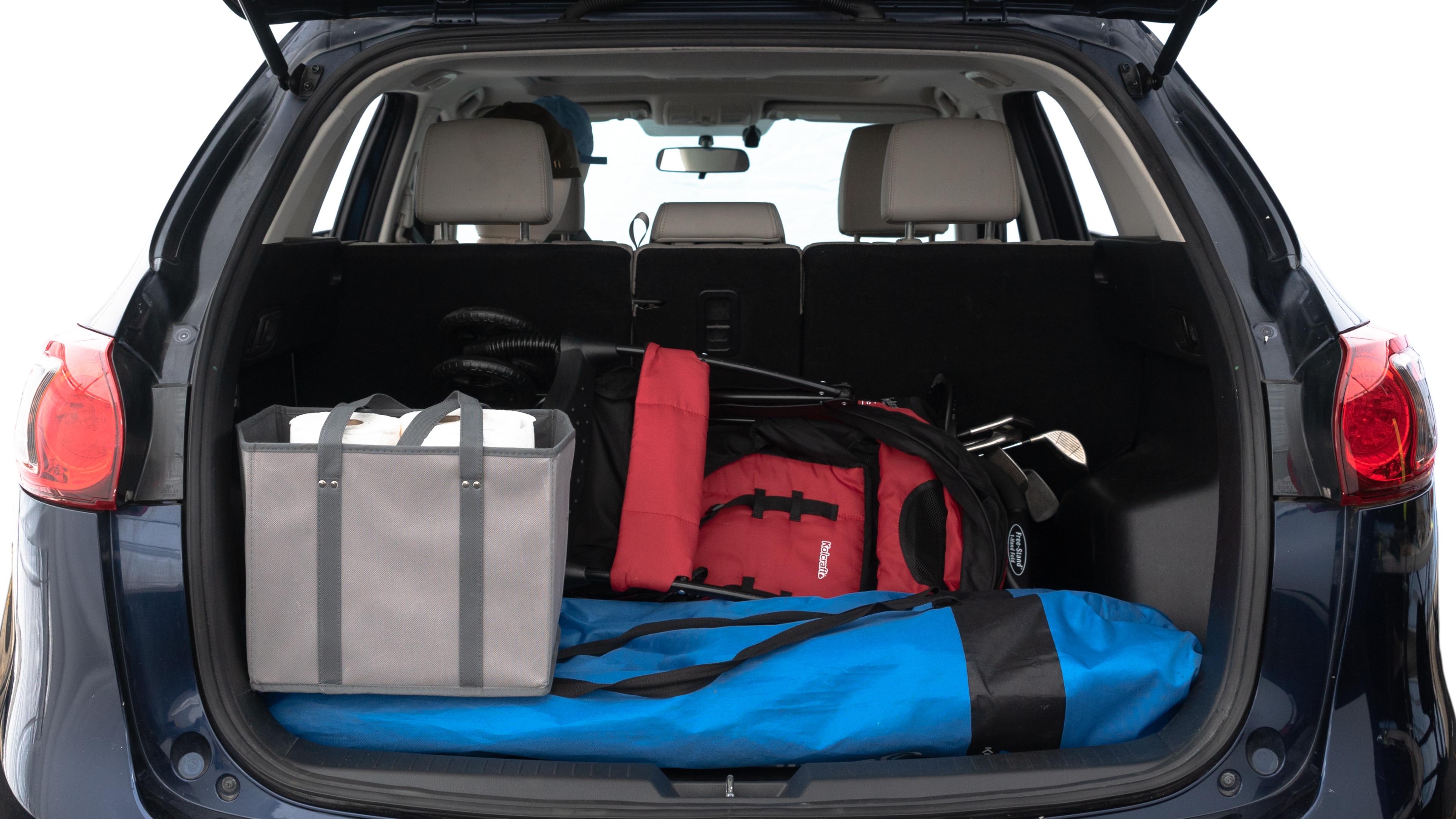 The trunk lid is open showing full view of the trunk. A baby stroller, three grocery carriers, two camping chairs in the carrying bag, and a set of golf clubs are placed inside.