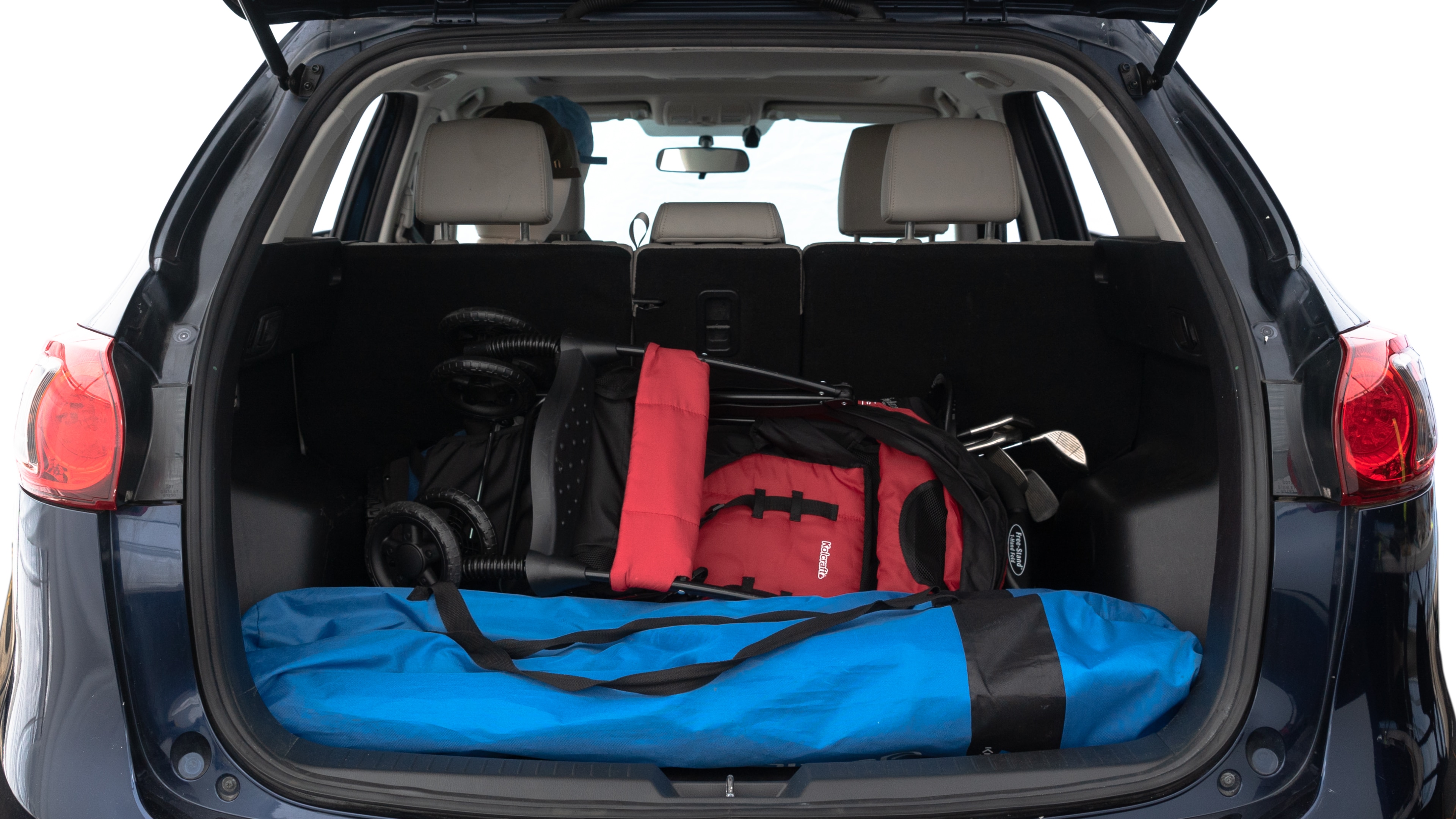 The trunk lid is open showing full view of the trunk. A baby stroller, three grocery carriers, two camping chairs in the carrying bag, and a set of golf clubs are placed inside.