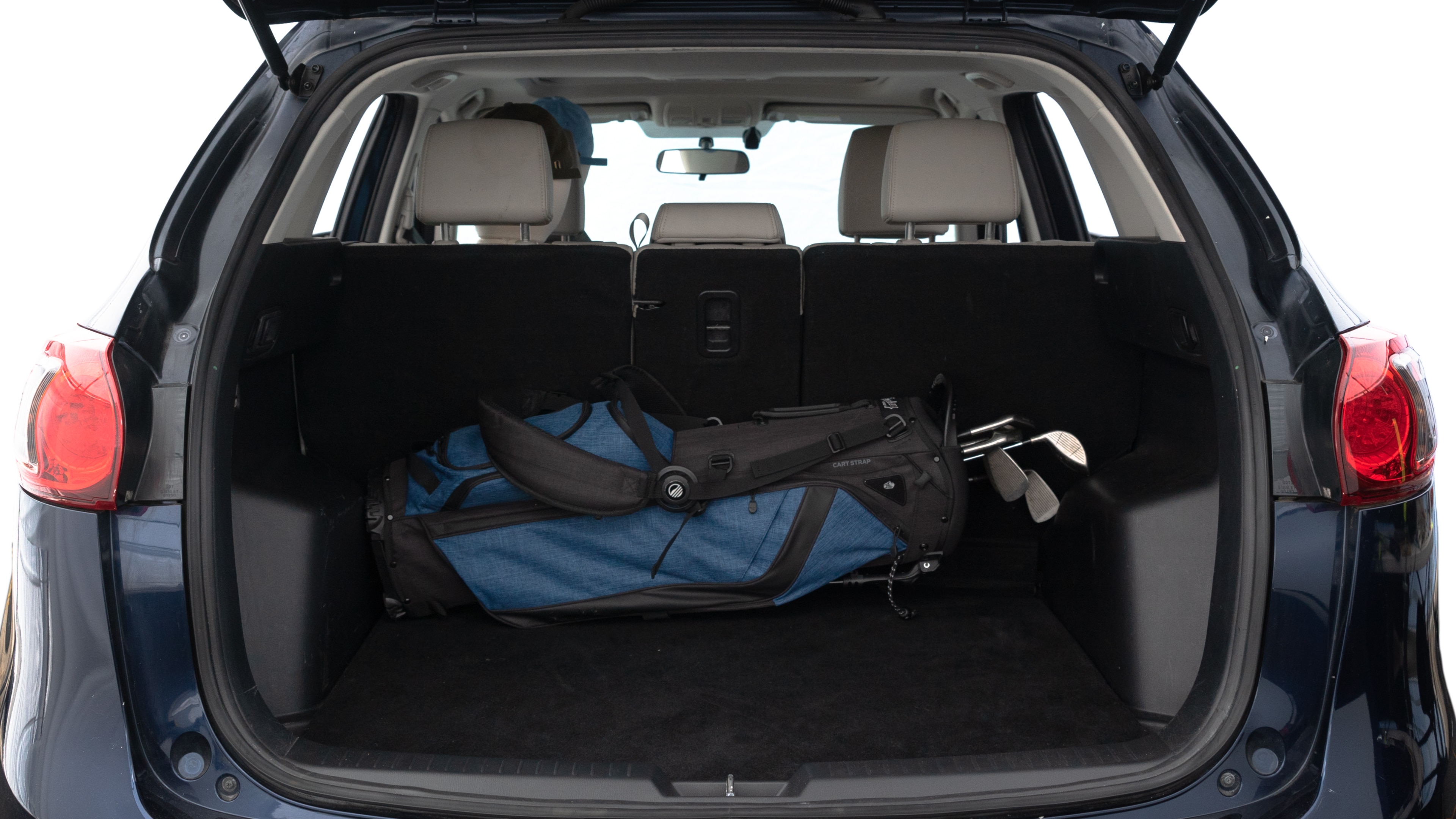The trunk lid is open showing full view of the trunk. A baby stroller, three grocery carriers, two camping chairs in the carrying bag, and a set of golf clubs are placed inside.