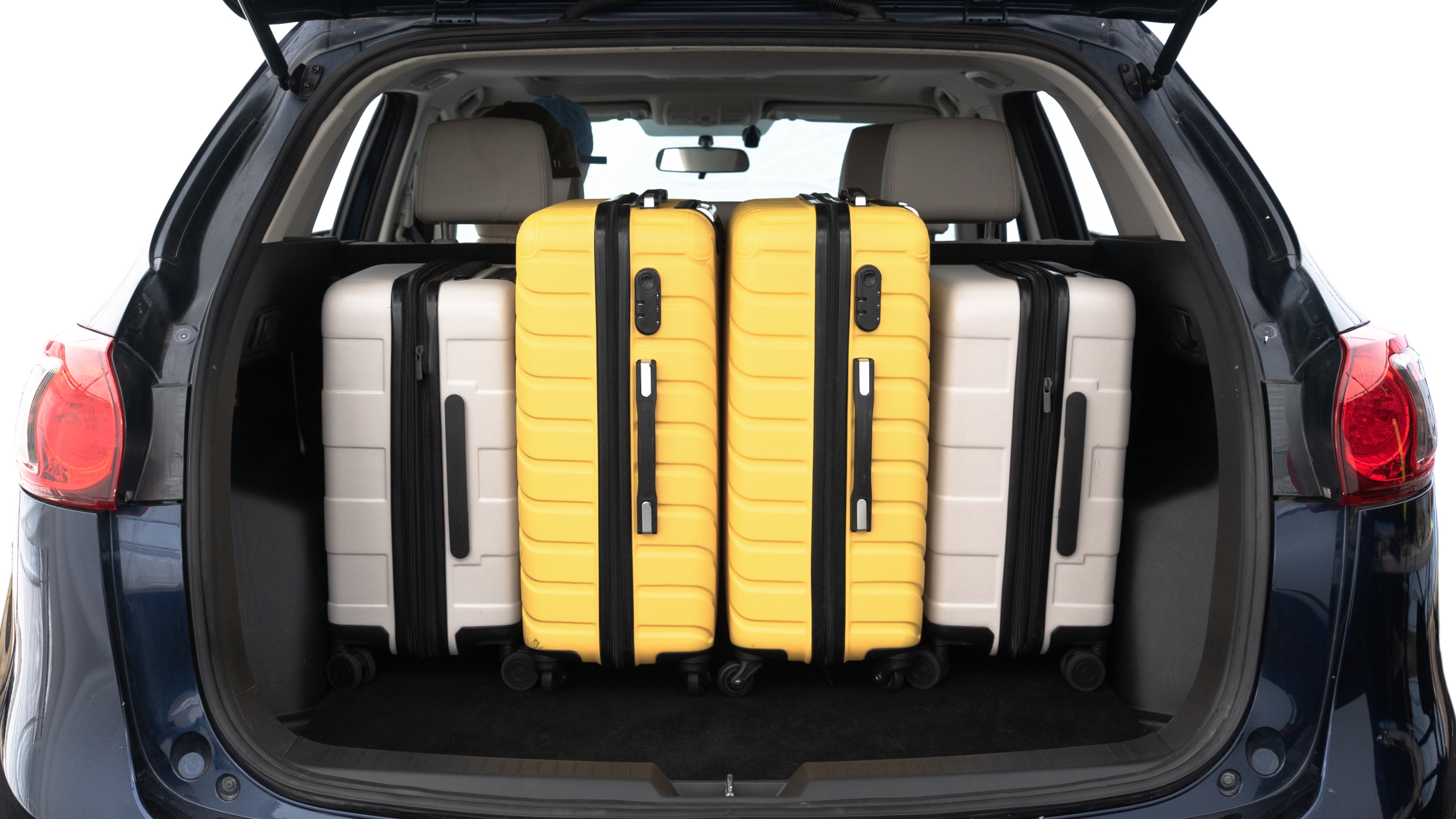 The trunk lid is open, showing full view of the trunk space. Two medium and two small suitcases are placed inside.
