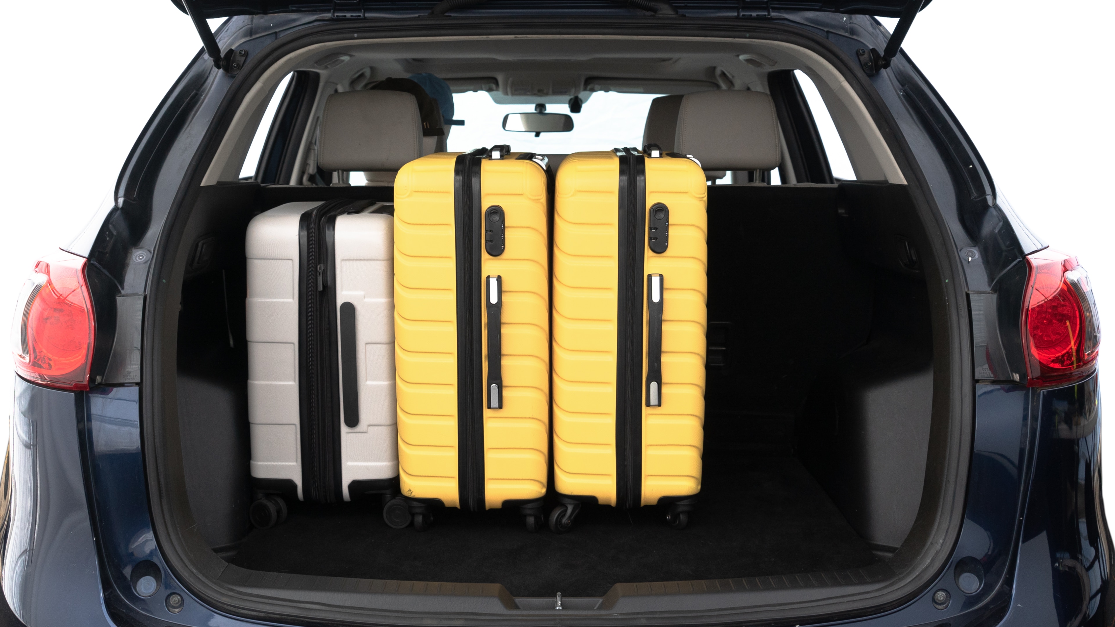 The trunk lid is open, showing full view of the trunk space. Two medium and two small suitcases are placed inside.