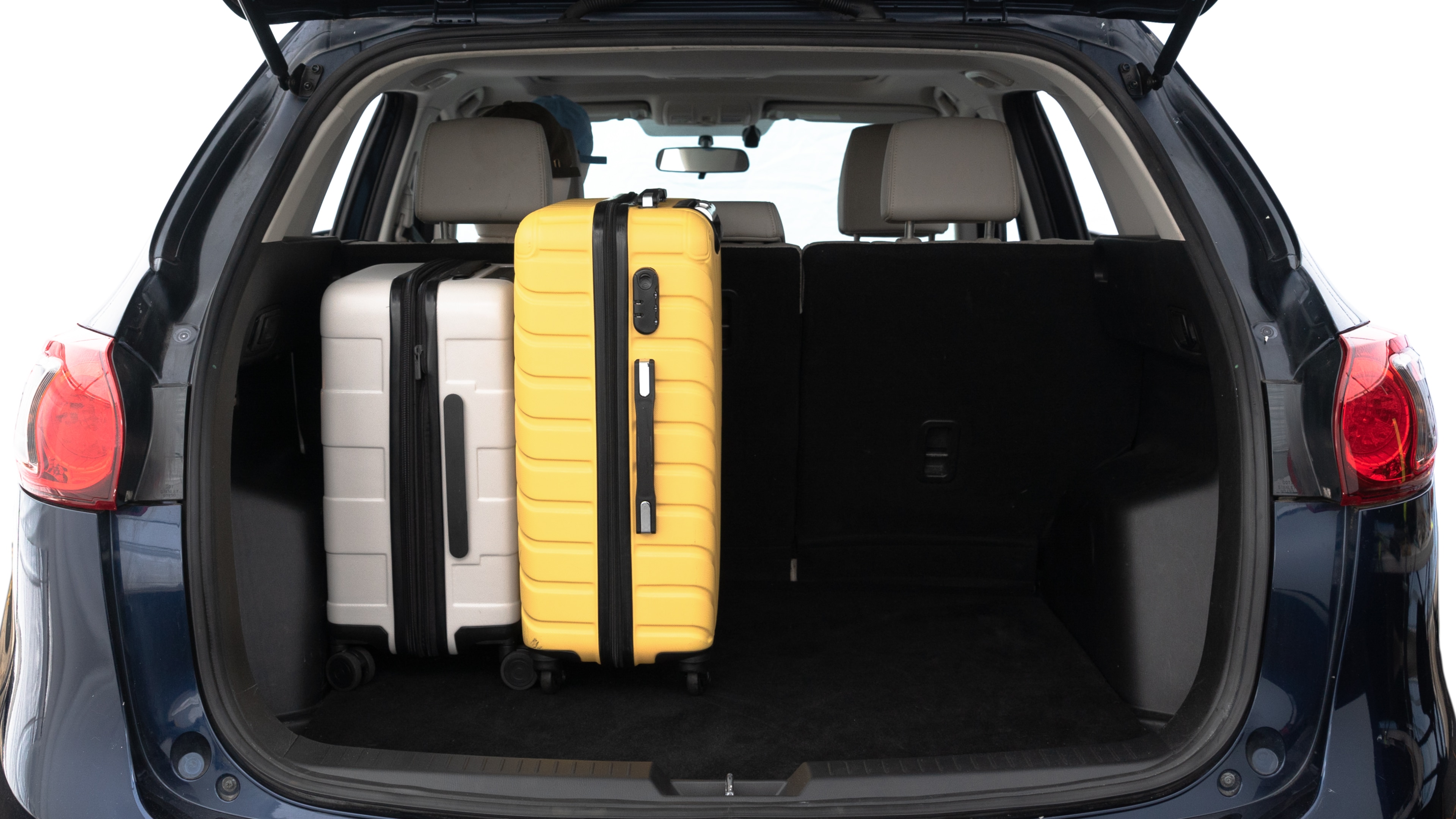 The trunk lid is open, showing full view of the trunk space. Two medium and two small suitcases are placed inside.