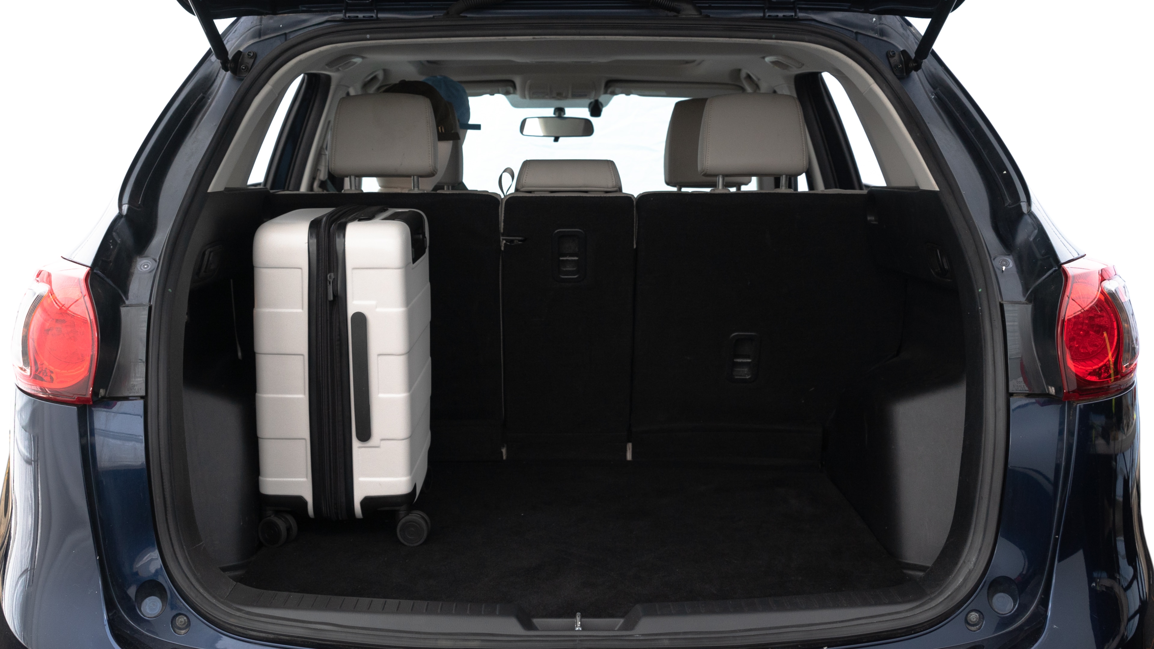 The trunk lid is open, showing full view of the trunk space. Two medium and two small suitcases are placed inside.