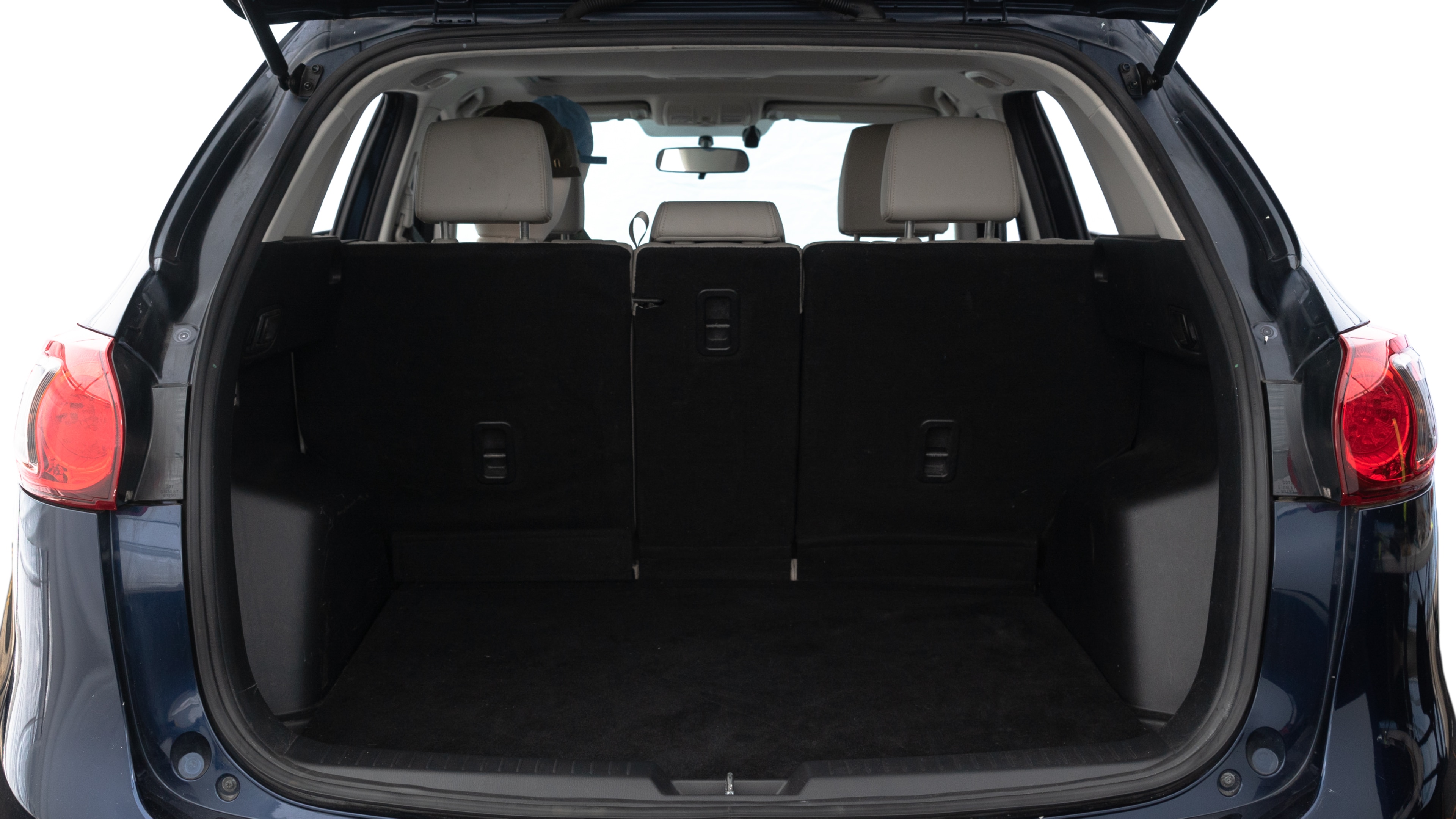 The trunk lid is open, showing full view of the trunk space. Two medium and two small suitcases are placed inside.