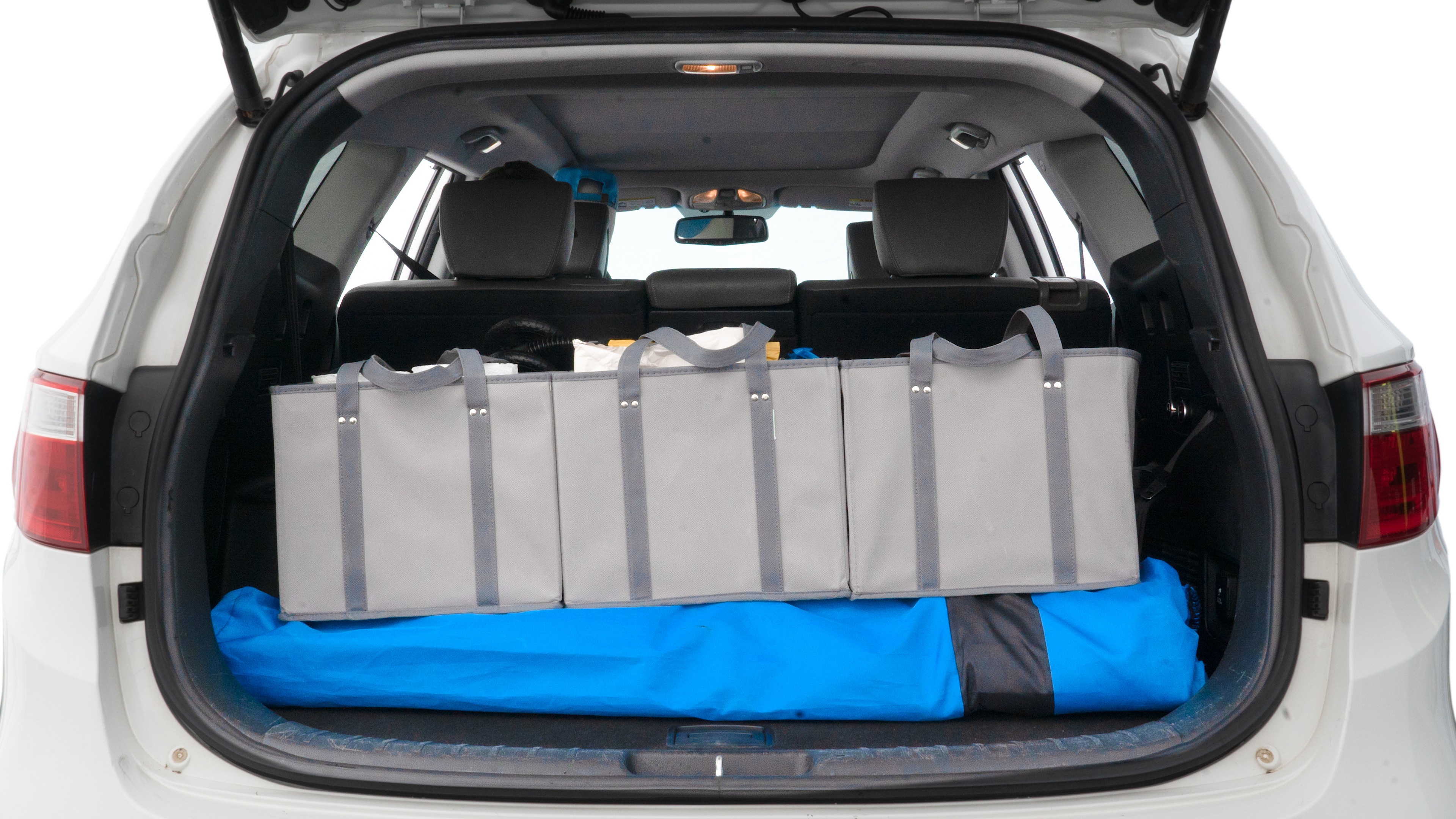 The trunk lid is open showing full view of the trunk. A baby stroller, three grocery carriers, two camping chairs in the carrying bag, and a set of golf clubs are placed inside.