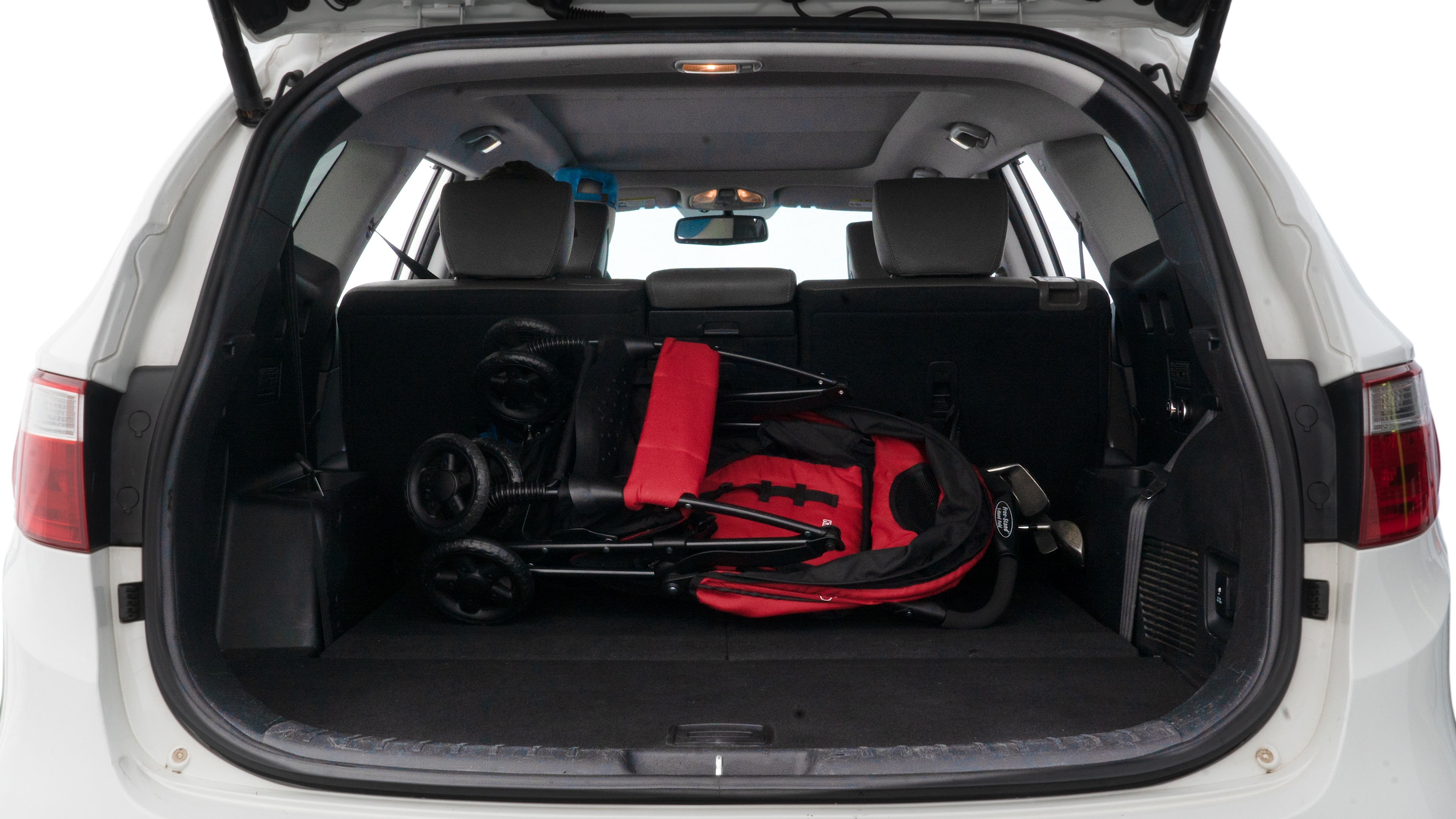 The trunk lid is open showing full view of the trunk. A baby stroller, three grocery carriers, two camping chairs in the carrying bag, and a set of golf clubs are placed inside.