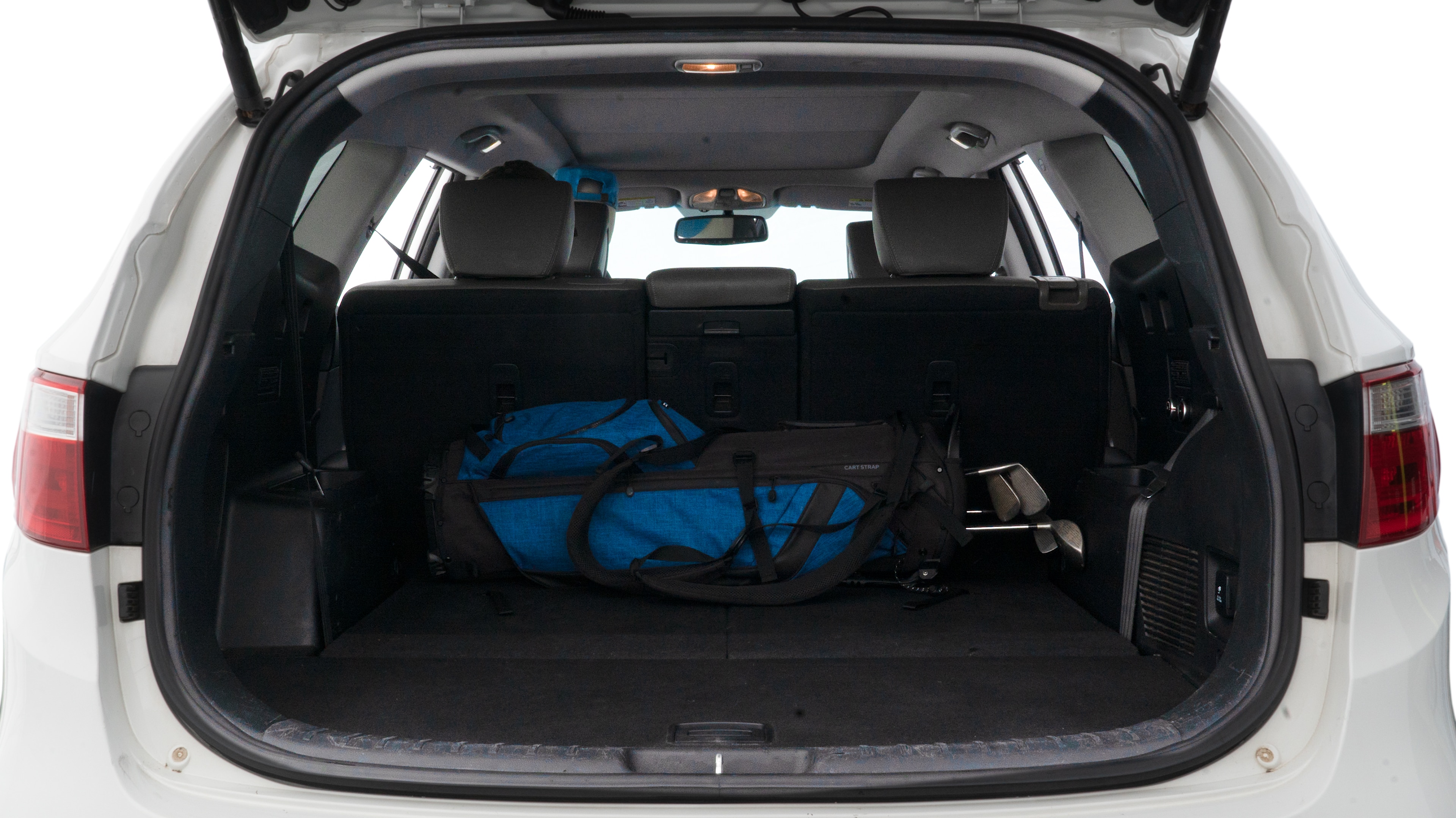 The trunk lid is open showing full view of the trunk. A baby stroller, three grocery carriers, two camping chairs in the carrying bag, and a set of golf clubs are placed inside.
