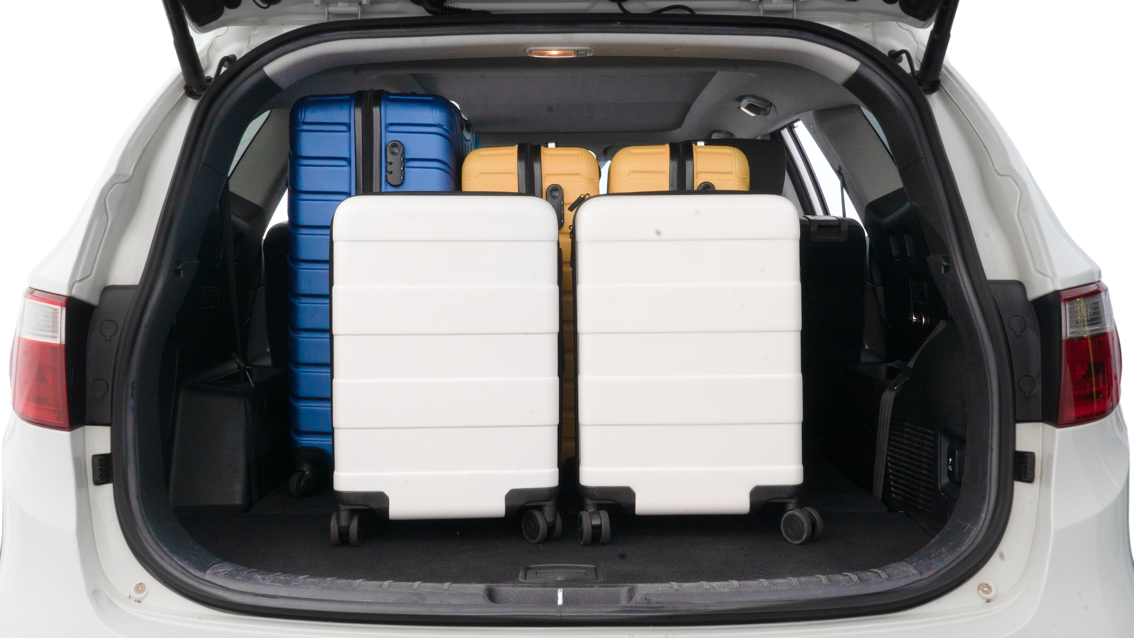 The trunk lid is open, showing full view of the trunk space. One large, two medium, and two small suitcases are placed inside.