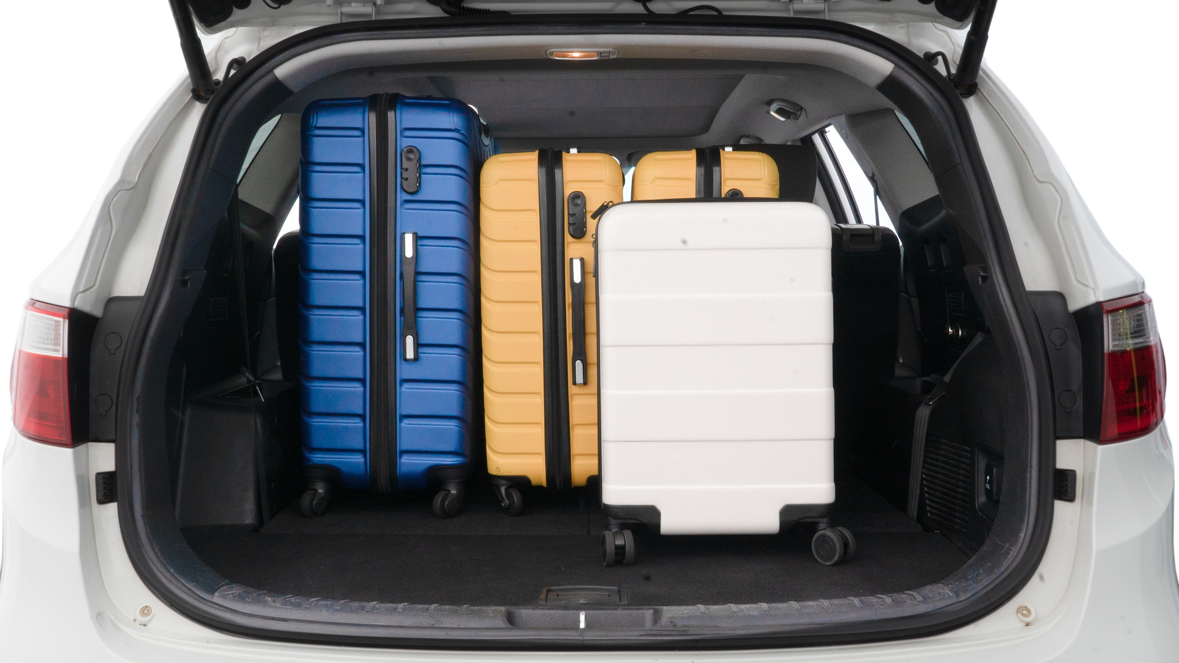The trunk lid is open, showing full view of the trunk space. One large, two medium, and two small suitcases are placed inside.