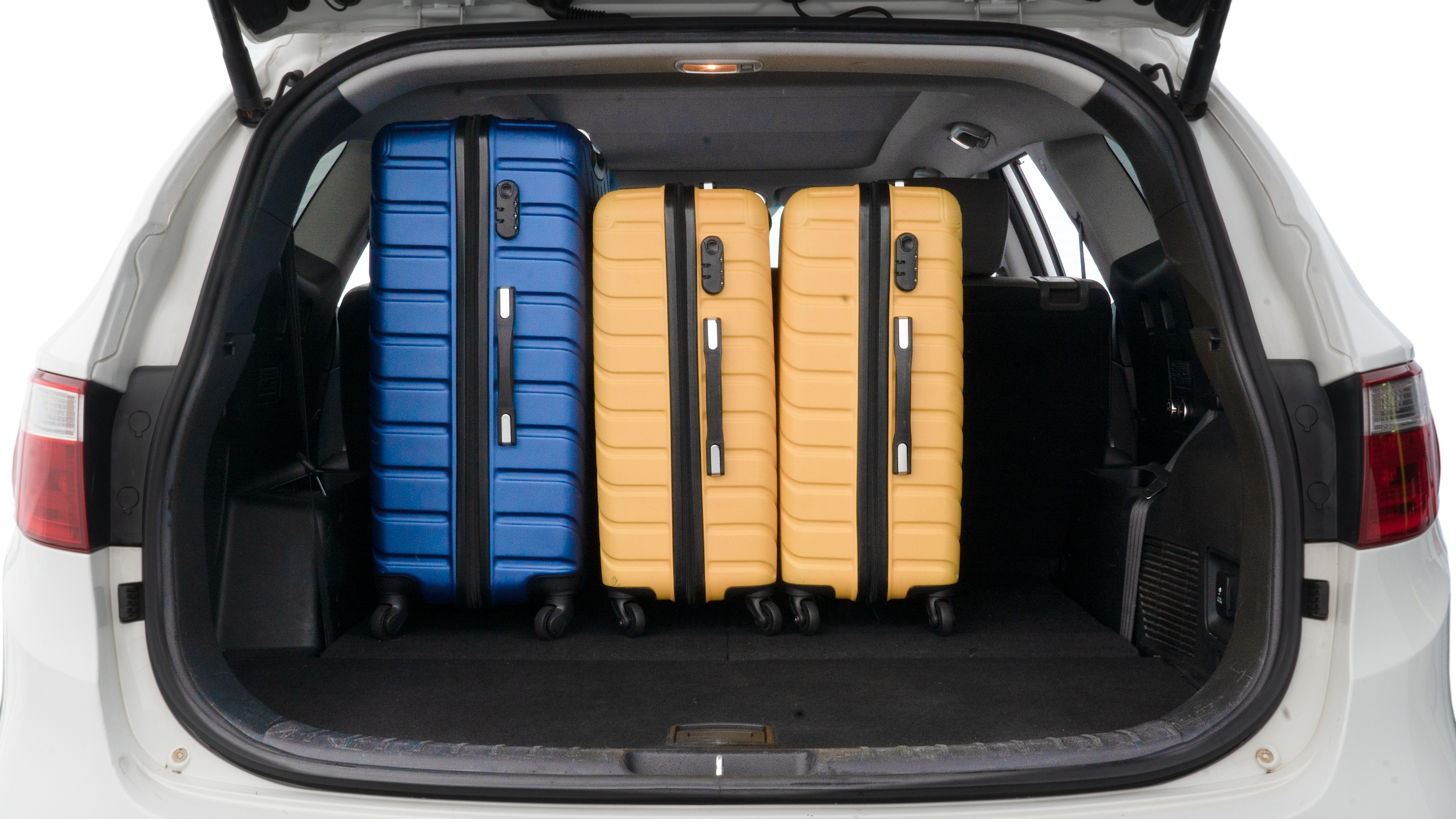 The trunk lid is open, showing full view of the trunk space. One large, two medium, and two small suitcases are placed inside.